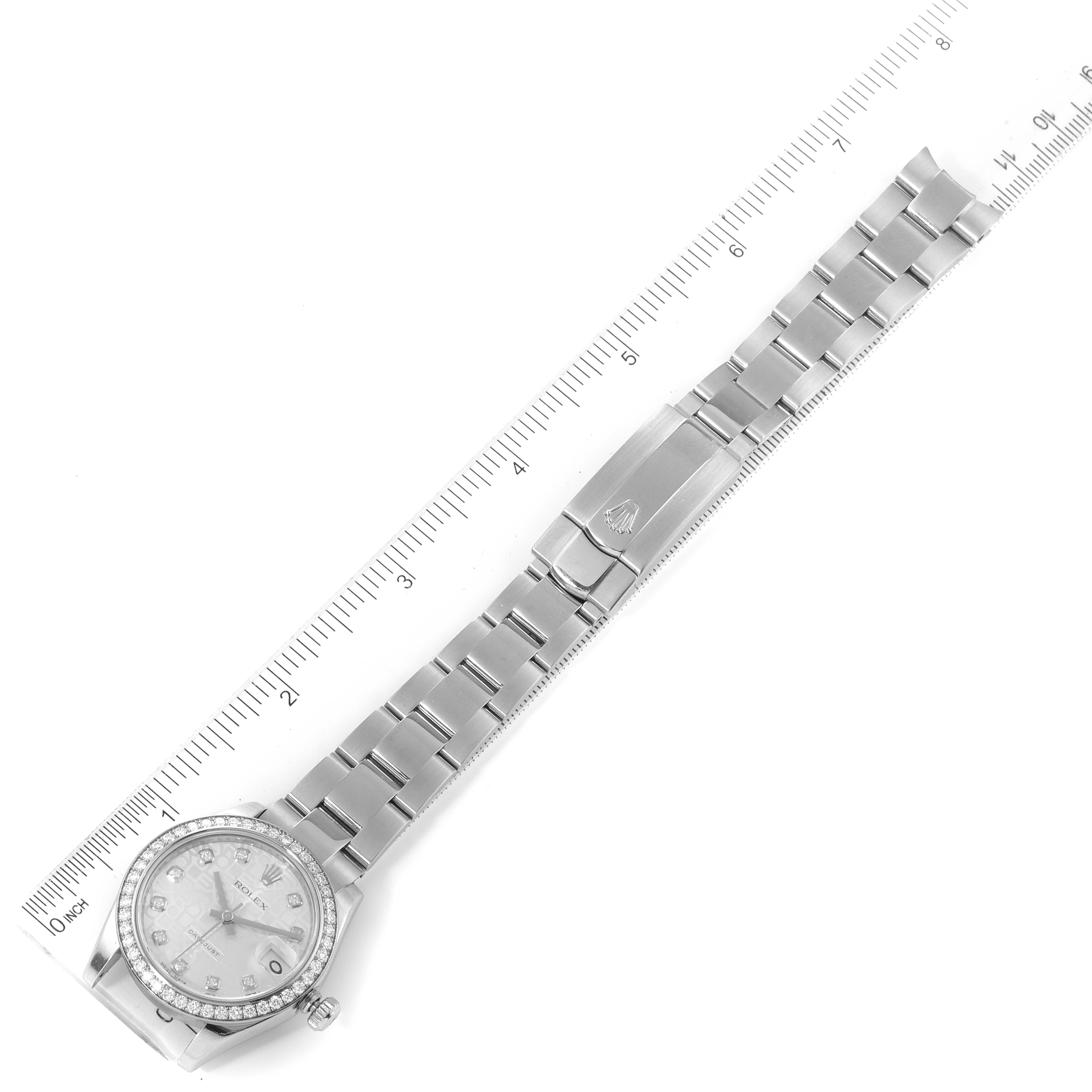 The image shows a top-down view of a Rolex Mid-Size 178384 Women
s Stainless Steel Silver Dial 178384 Women
s Stainless Steel Silver Dial watch, displaying its face, bezel, bracelet, and clasp next to a ruler for size reference.