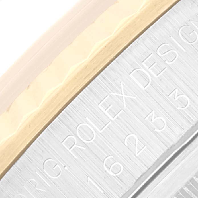This close-up image of a Rolex Datejust 16233 Men's Steel and Gold (two tone) Beige Dial 16233 Men's Steel and Gold (two tone) Beige Dial watch shows the engraved design on the outer edge of the case and part of the fluted bezel.