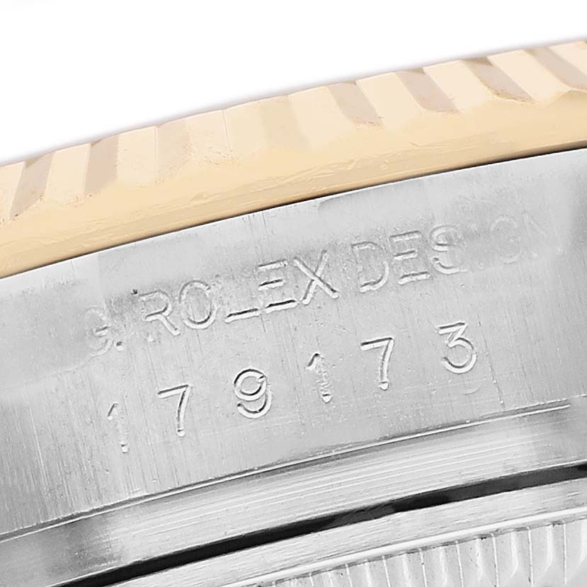The image shows a close-up of the engraved side of a Rolex Datejust 179173 Women's Stainless Steel Silver Dial watch, focusing on its bezel and serial number.