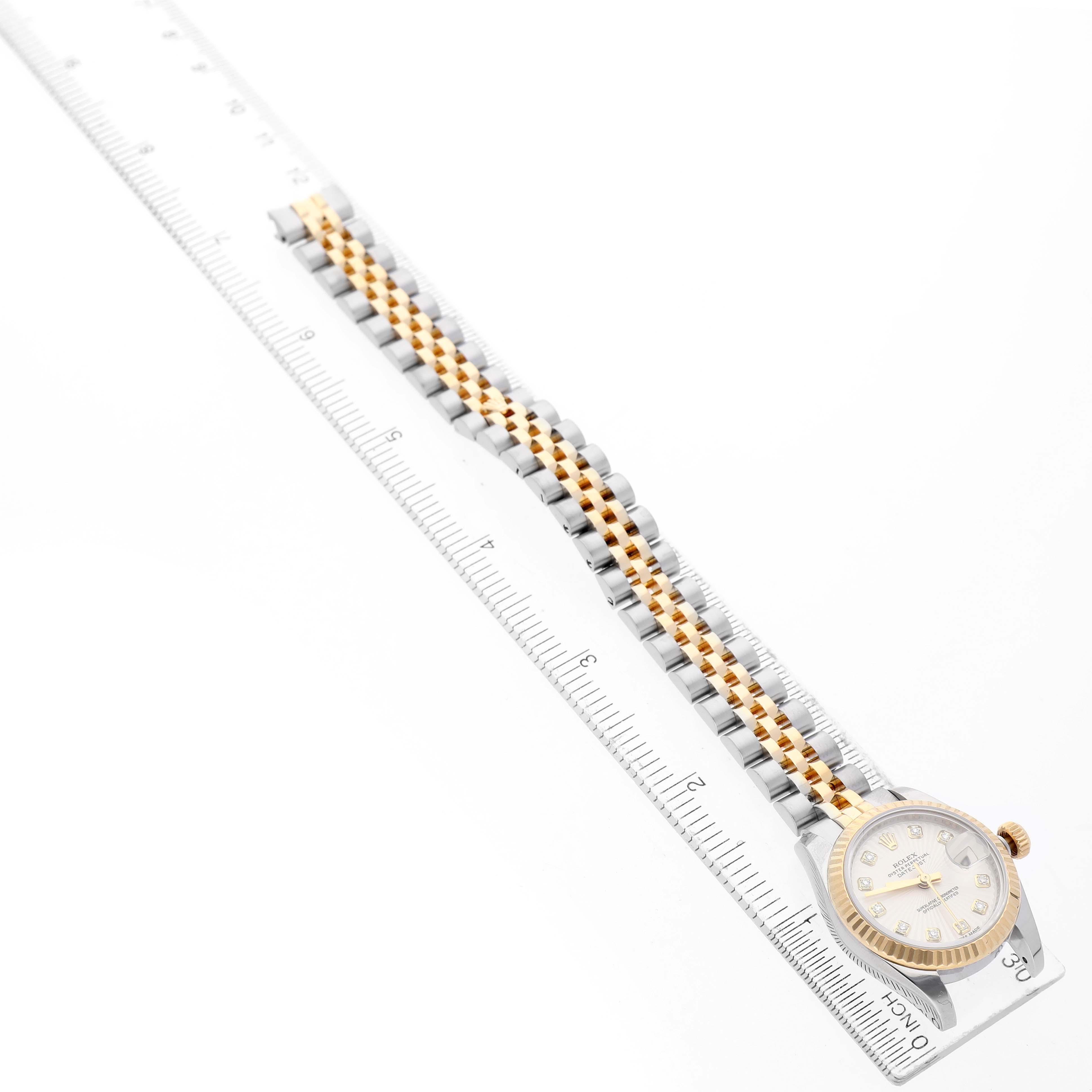 The Rolex Datejust 179173 Women's Stainless Steel Silver Dial watch is shown from an angled overhead view, highlighting the bracelet and face alongside a ruler.