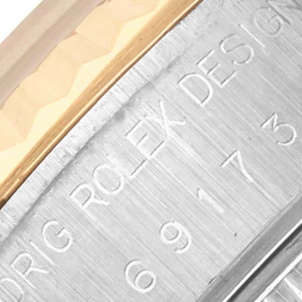 The image shows the side edge of a Rolex Datejust 69173 Women's Steel and Gold (two tone) Champagne Dial 69173 Women's Steel and Gold (two tone) Champagne Dial watch with engravings on its bezel and a gold accent.