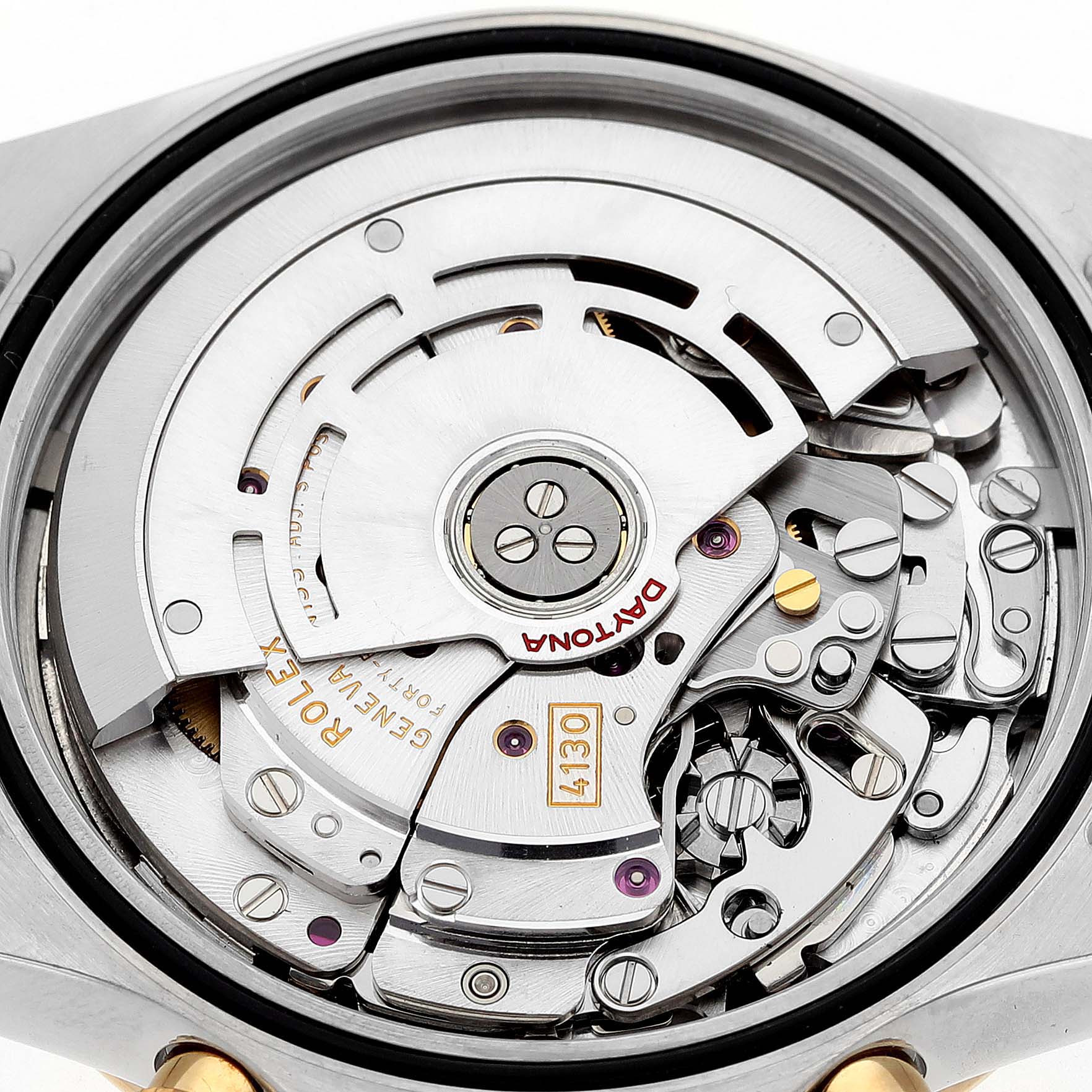 The image shows the inner mechanism of a Rolex Daytona 116523 Men's Steel and Gold (two tone) Silver Dial, highlighting the movement with visible gears and engravings.
