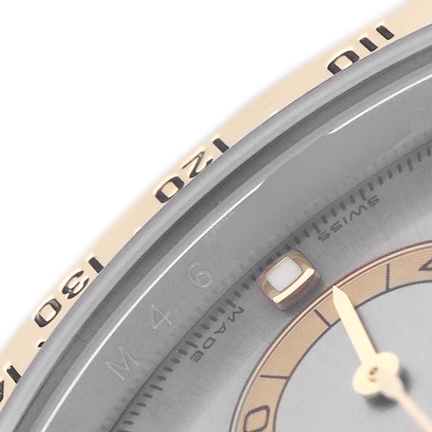 The image shows a close-up of the bezel and part of the dial of a Rolex Daytona 116523 Men's Steel and Gold (two tone) Silver Dial watch.