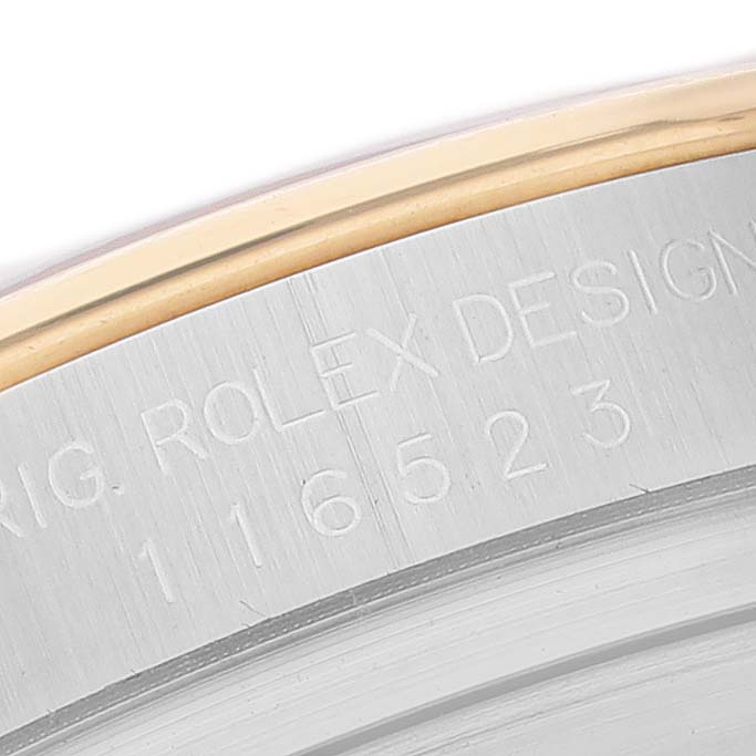 The image shows a close-up of the Rolex Daytona 116523 Men's Steel and Gold (two tone) Silver Dial's engraved case edge, displaying text and reference numbers.