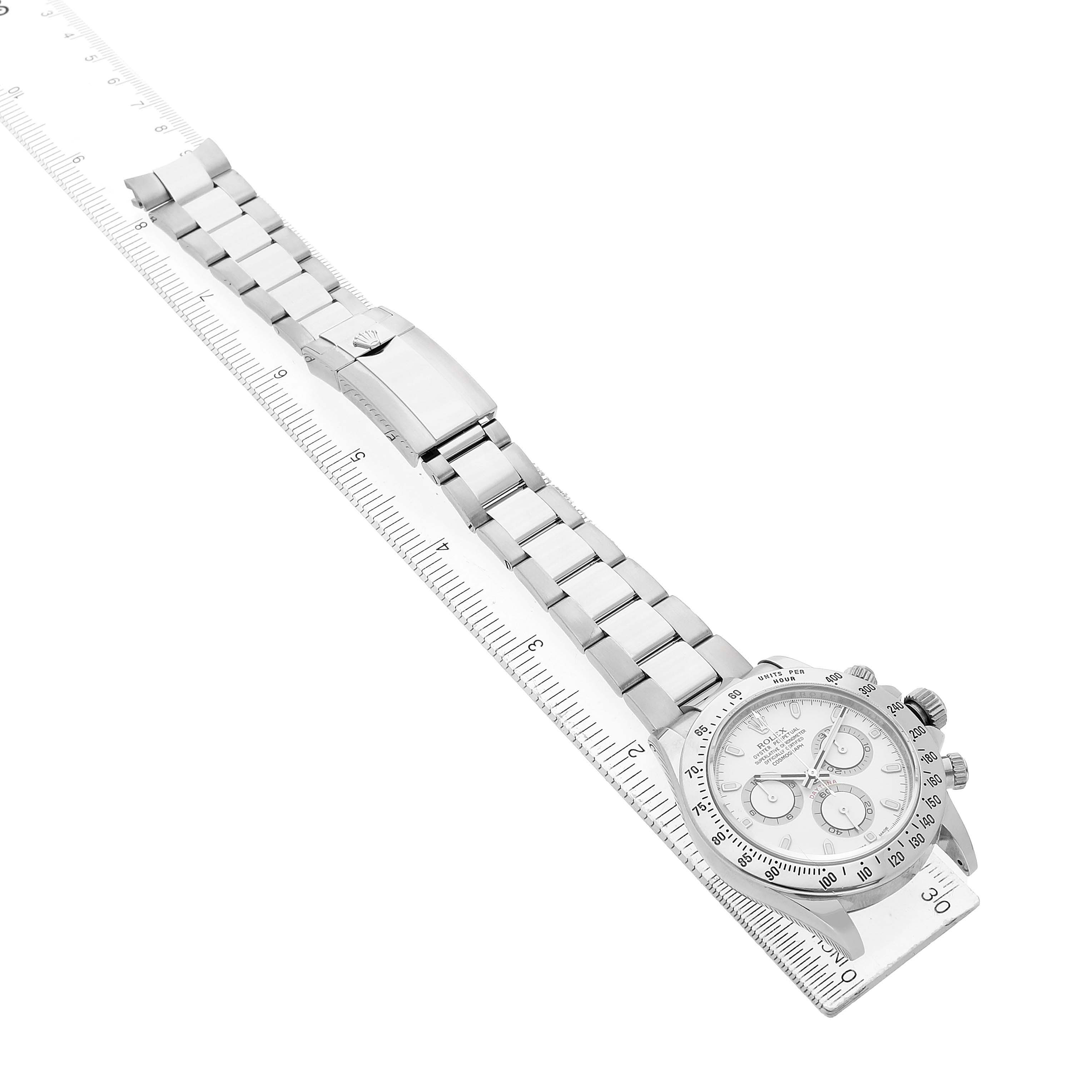 The Rolex Daytona 116520 Men's Stainless Steel White Dial watch is shown at an angle highlighting the full bracelet and face, placed on a ruler for scale.