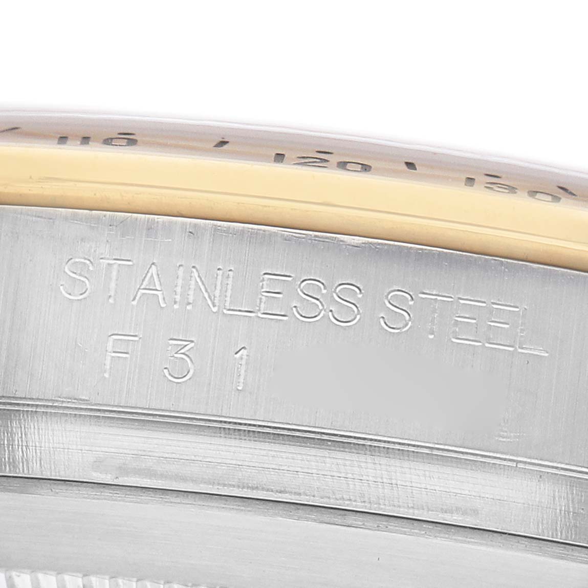 The image shows a close-up of a Rolex Daytona 116523 Men's Steel and Gold (two tone) White Dial watch's side, highlighting the stainless steel engraving.