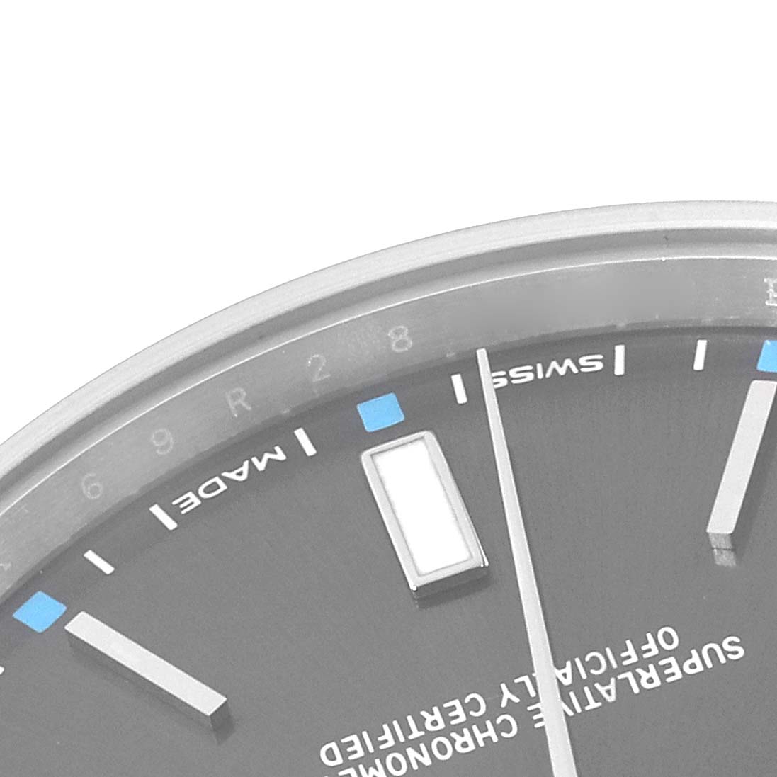 The image shows a close-up of the dial and markers of a Rolex Oyster Perpetual 114300 Men's Stainless Steel Grey Dial 114300 Men's Stainless Steel Grey Dial watch.