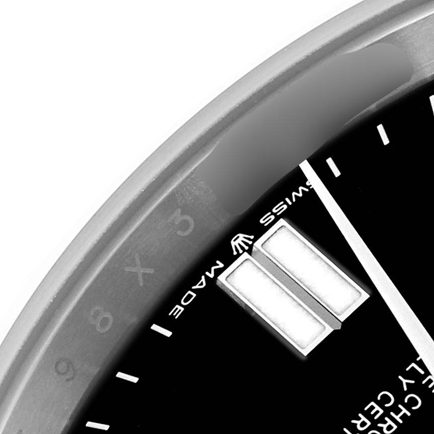 The image shows a close-up of the Rolex Oyster Perpetual 124300 Men
s Stainless Steel Black Dial 124300 Men
s Stainless Steel Black Dial watch face, focusing on the markers, bezel, and partial text.