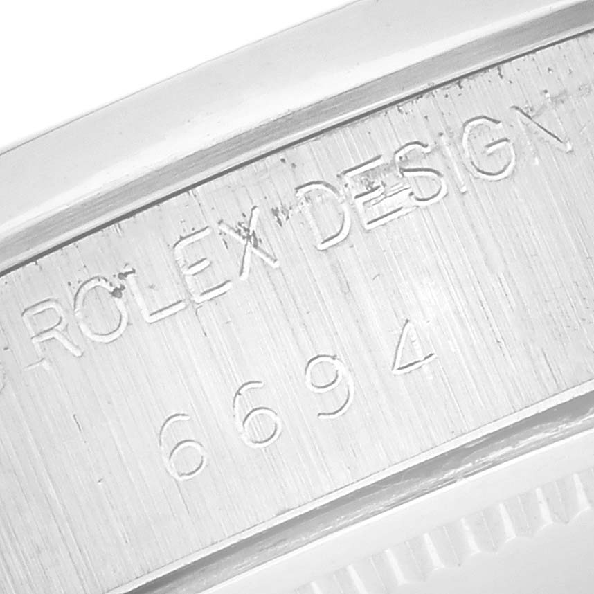 The image shows a close-up of the Rolex Date 6694 Men's Stainless Steel Silver Dial 6694 Men's Stainless Steel Silver Dial model's case with engraved design numbers.