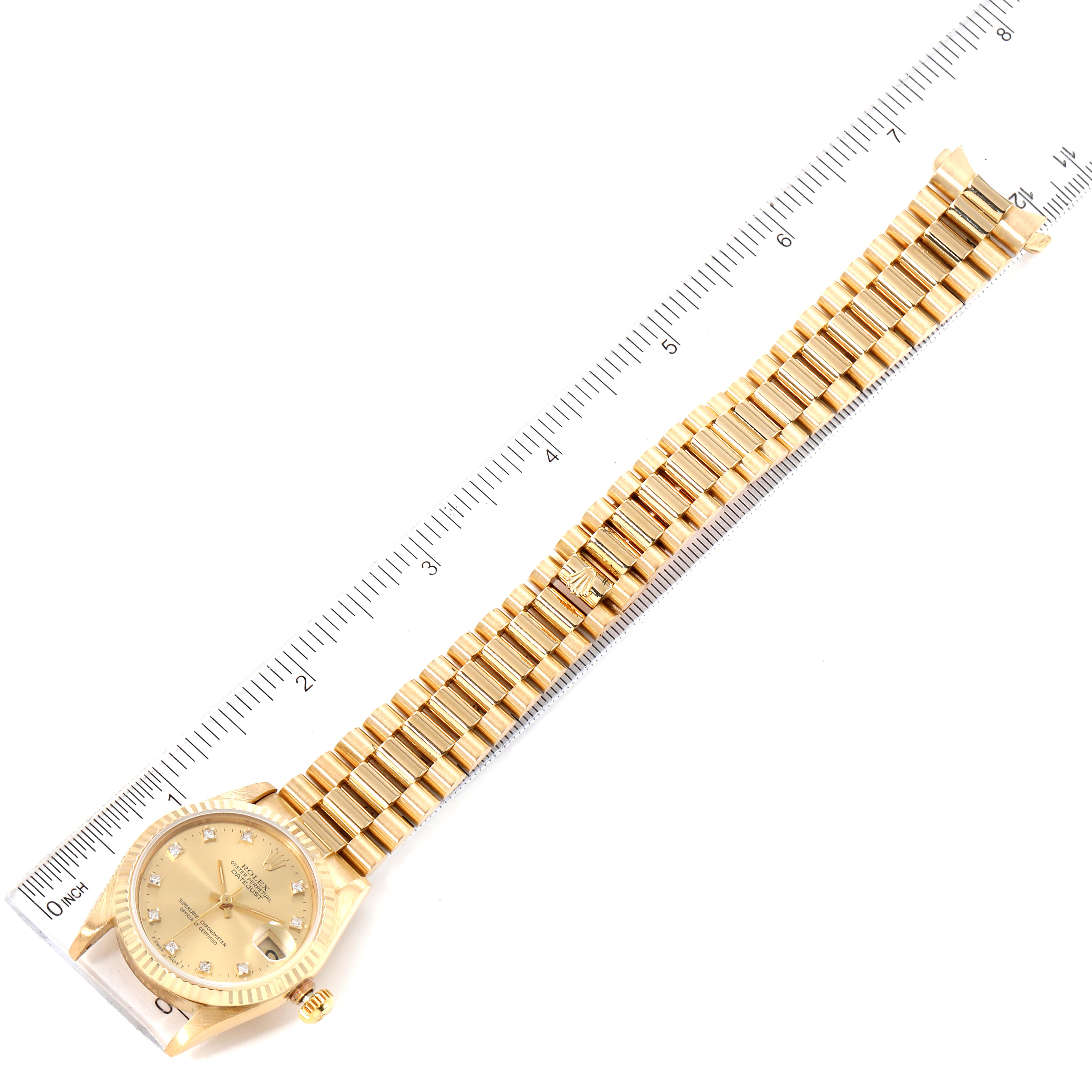 The image shows an overhead view of a Rolex President 68278 Women
s Yellow Gold Champagne Dial 68278 Women
s Yellow Gold Champagne Dial model watch, displaying the face, crown, and full bracelet laid out beside a ruler.