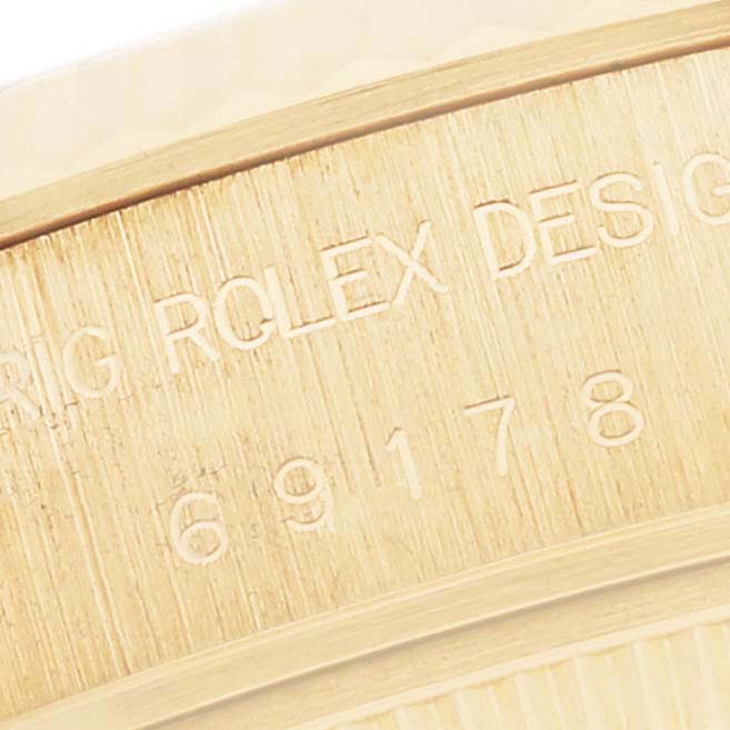 The image shows a close-up of the engraved side view of a Rolex President 69178 Women's Yellow Gold Champagne Dial 69178 Women's Yellow Gold Champagne Dial model, highlighting the serial and model numbers.