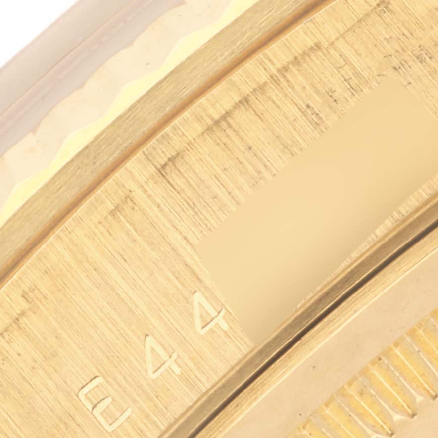 The image shows a close-up of the engraved bezel of a Rolex President 18238 Men's Yellow Gold Champagne Dial 18238 Men's Yellow Gold Champagne Dial watch at an angle, highlighting its brushed gold finish.