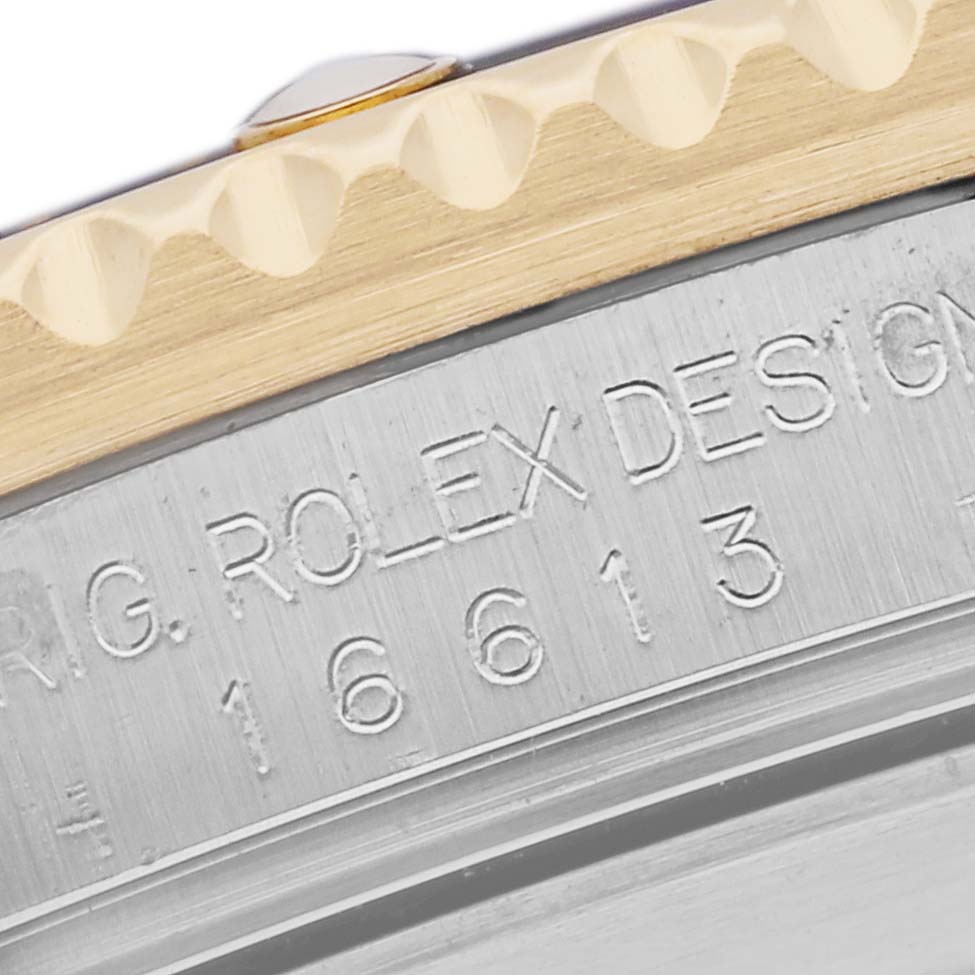 This image shows a close-up angle of the Rolex Submariner 16613 Men's Steel and Gold (two tone) Black Dial 16613 Men's Steel and Gold (two tone) Black Dial's bezel edge and engraved caseback.