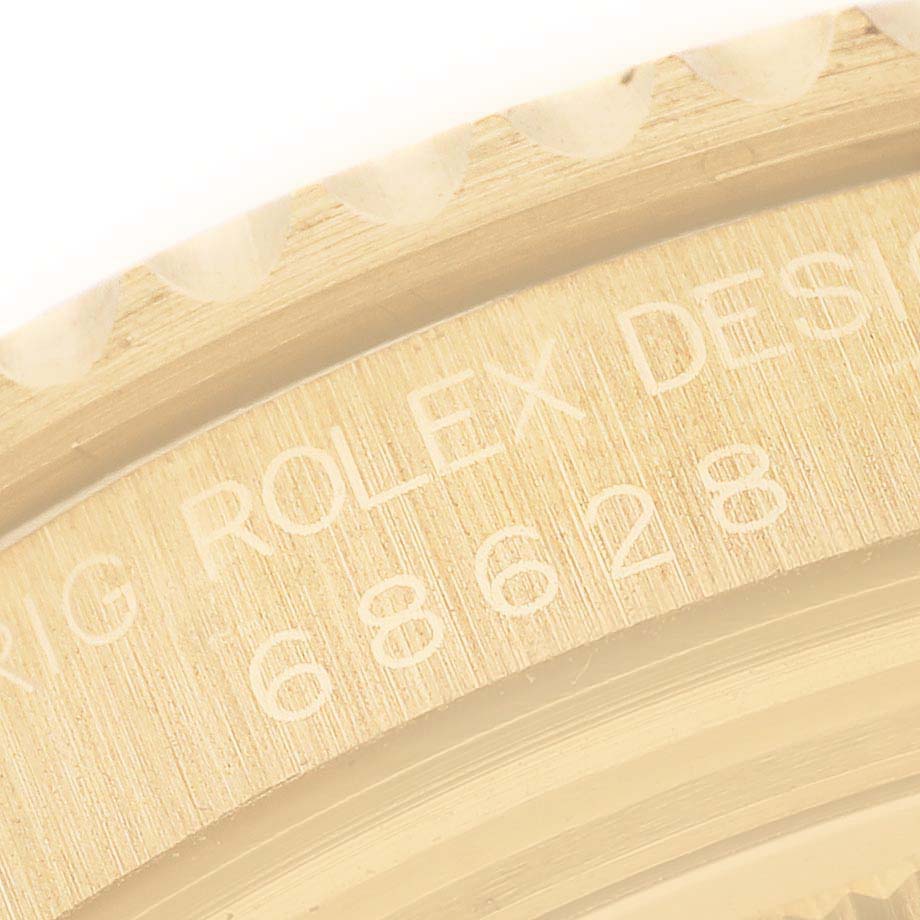 The image shows a close-up of the engraved bezel and case of a Rolex Yacht-Master 68628 Men's Yellow Gold Blue Dial 68628 Men's Yellow Gold Blue Dial watch.
