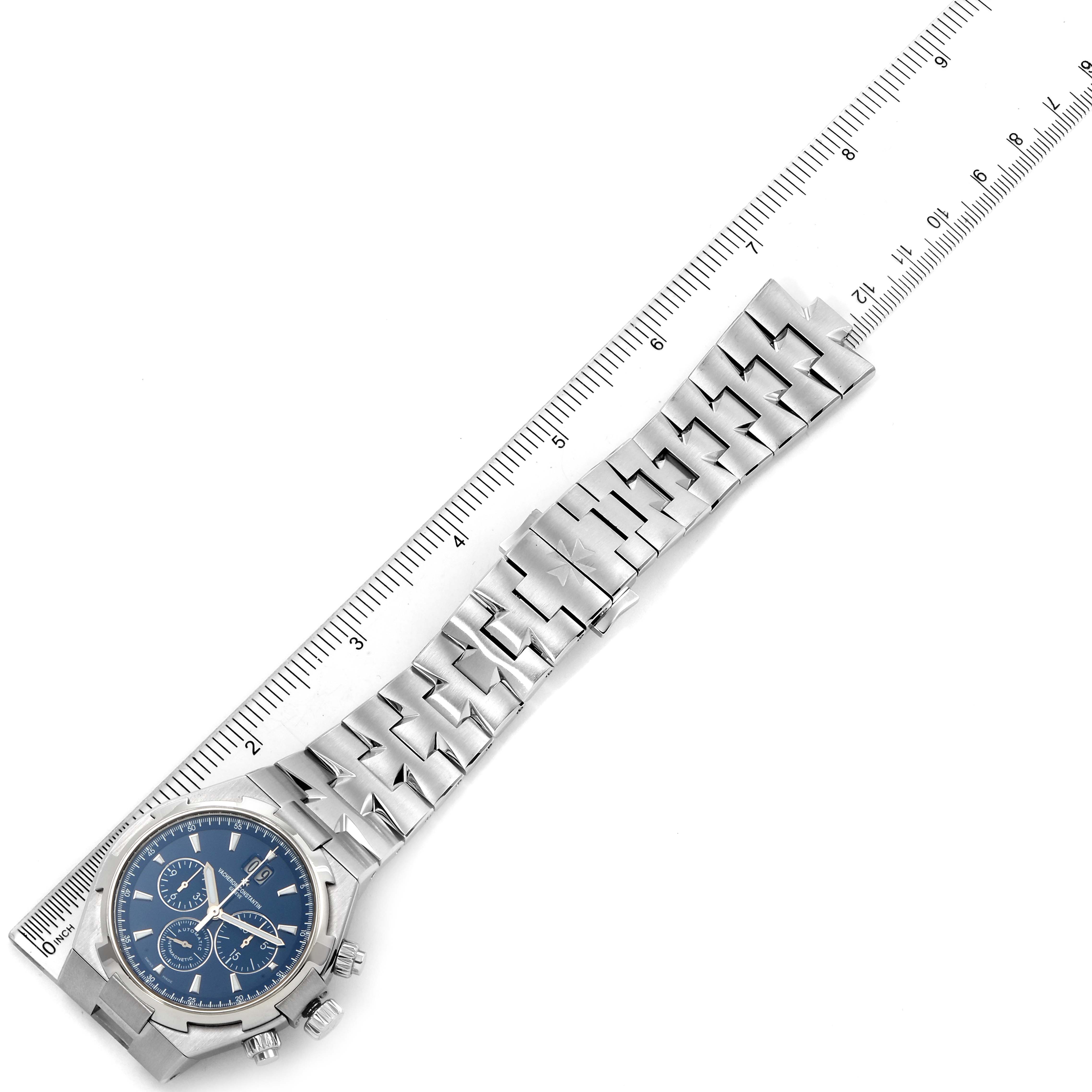 This image shows the Vacheron Constantin Overseas 49150.B01A.9097 Men's Stainless Steel Blue Dial 49150.B01A.9097 Men's Stainless Steel Blue Dial watch with a blue dial and silver bracelet, positioned alongside a ruler for measurement.