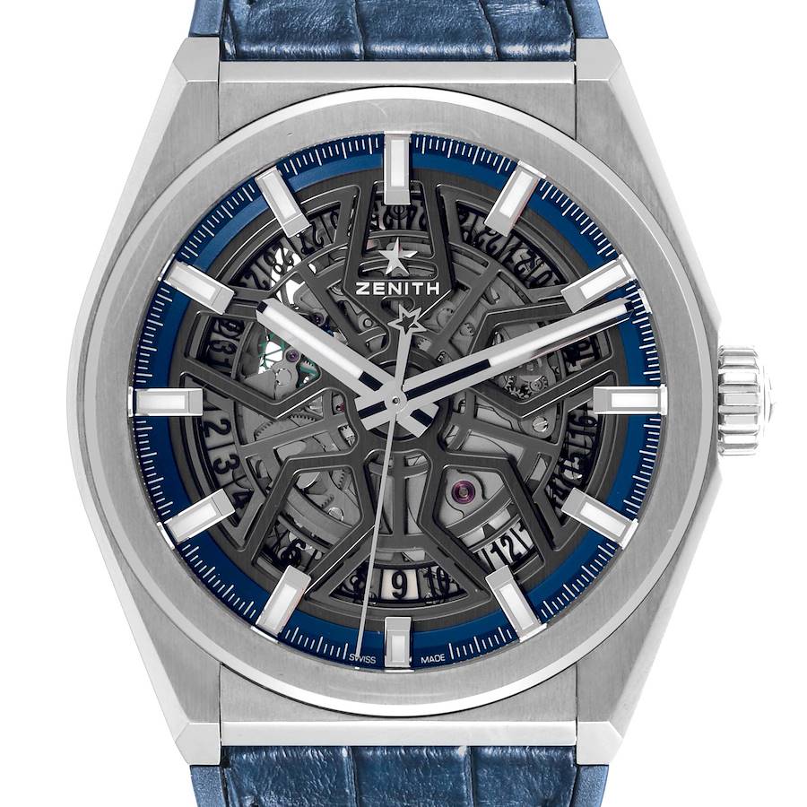 The Zenith Defy watch is shown from a front angle, highlighting its skeleton dial, blue accents, and metal case.