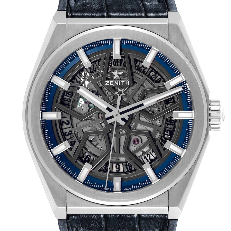 The Zenith Defy watch is shown from a front angle, highlighting its skeleton dial and visible mechanism.