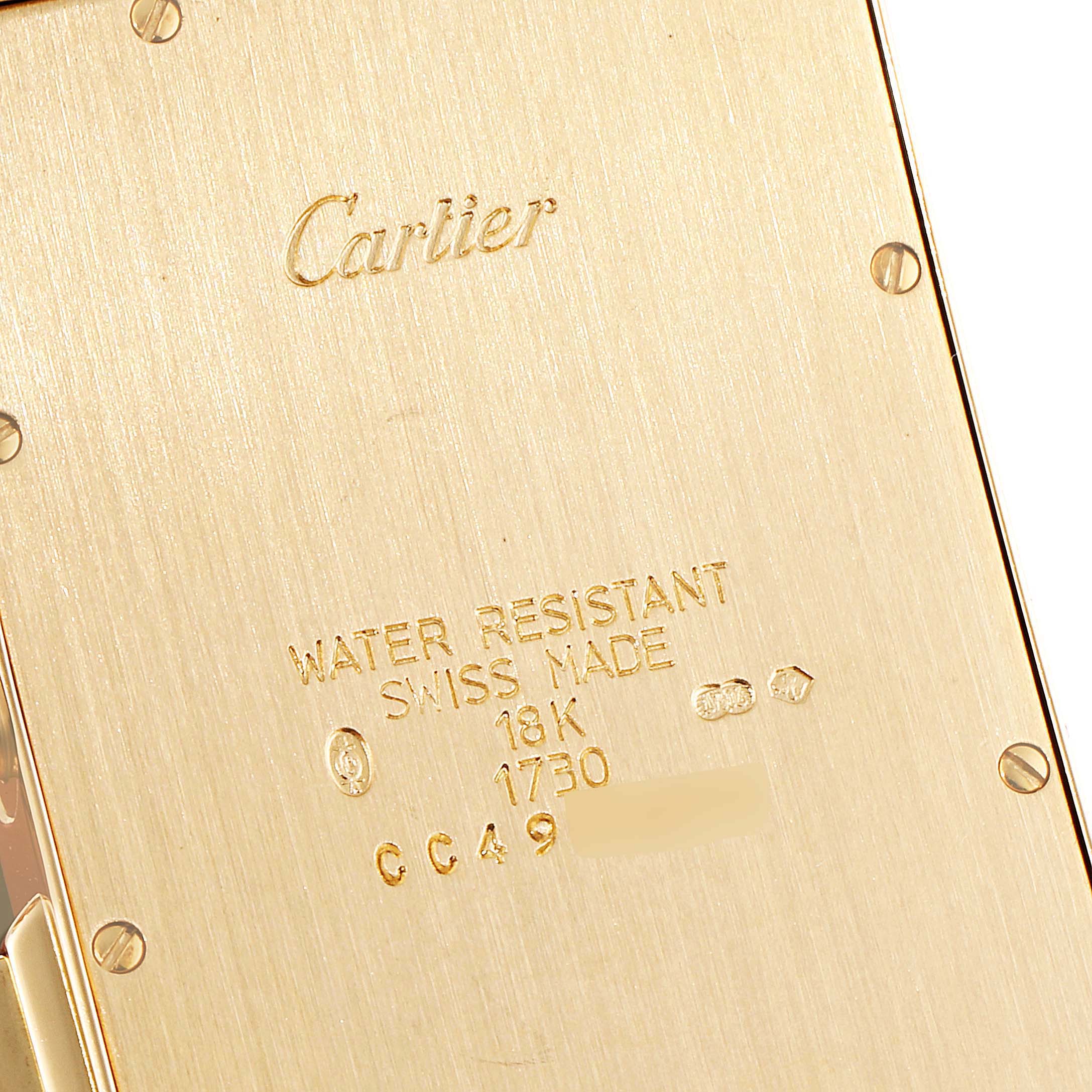 This image shows the back case of a Cartier Tank Americaine W2601156 Men
s Yellow Gold Silver Dial W2601156 Men
s Yellow Gold Silver Dial watch, highlighting its engravings and gold finish.