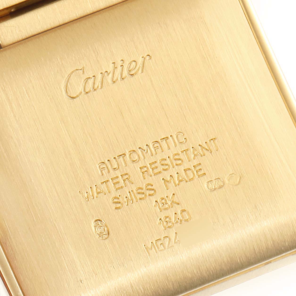 The image shows a close-up of the back case of a Cartier Tank Française watch, highlighting engraved details.