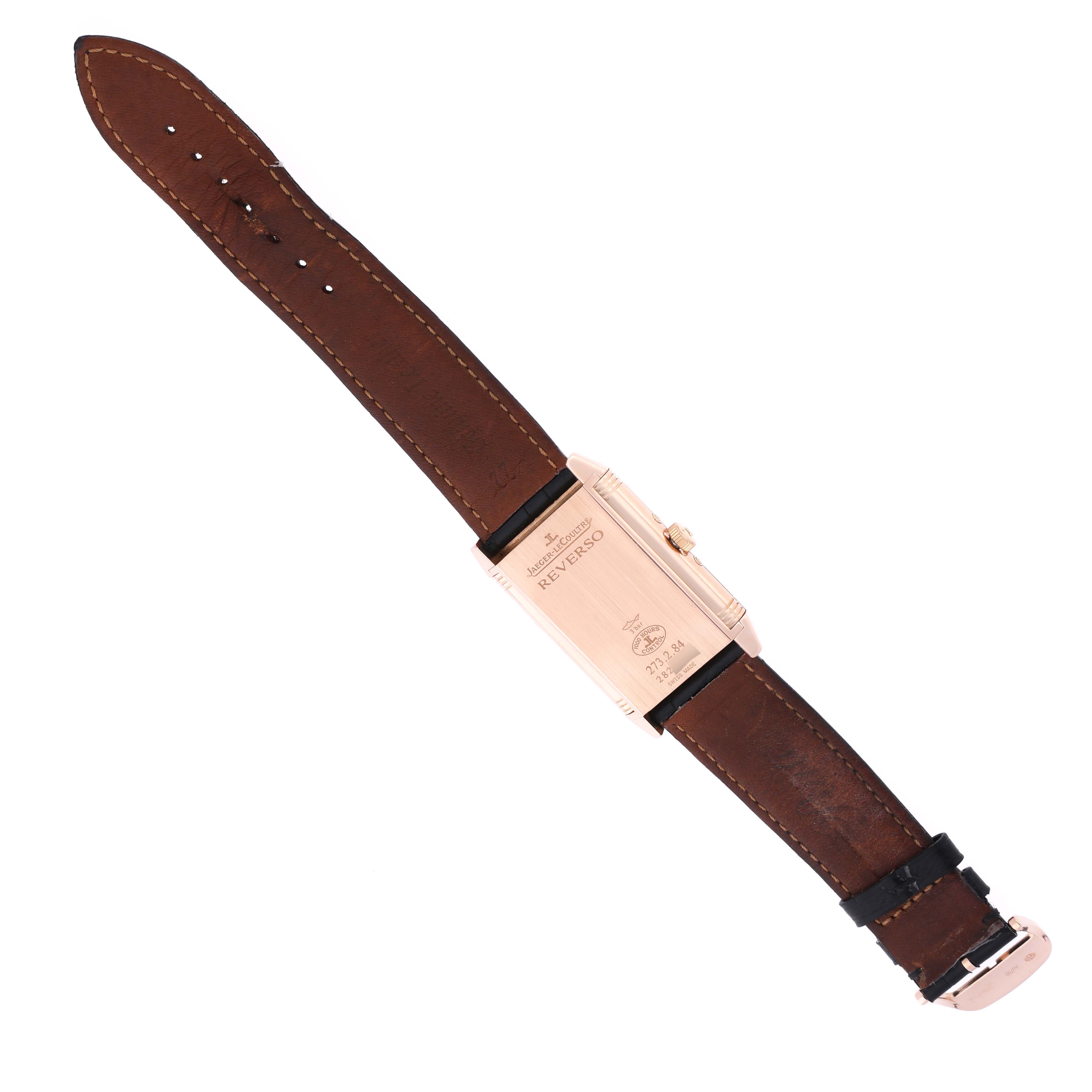 The Jaeger-LeCoultre Reverso watch is shown from the back, highlighting its case and brown leather strap.