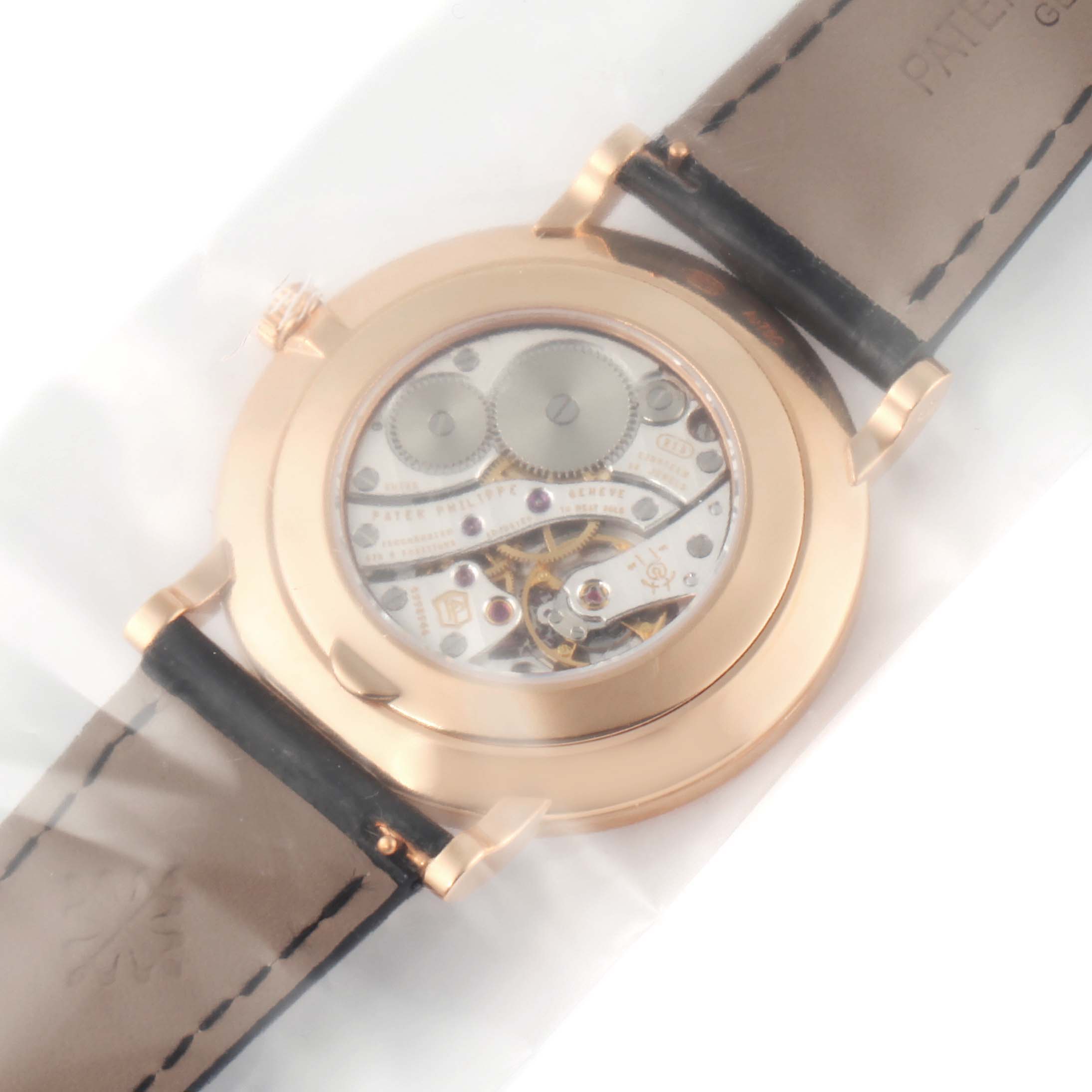 The image shows the back view of a Patek Philippe Calatrava 5116R Men's Rose Gold White Dial 5116R Men's Rose Gold White Dial model, revealing its mechanical movement and leather straps.