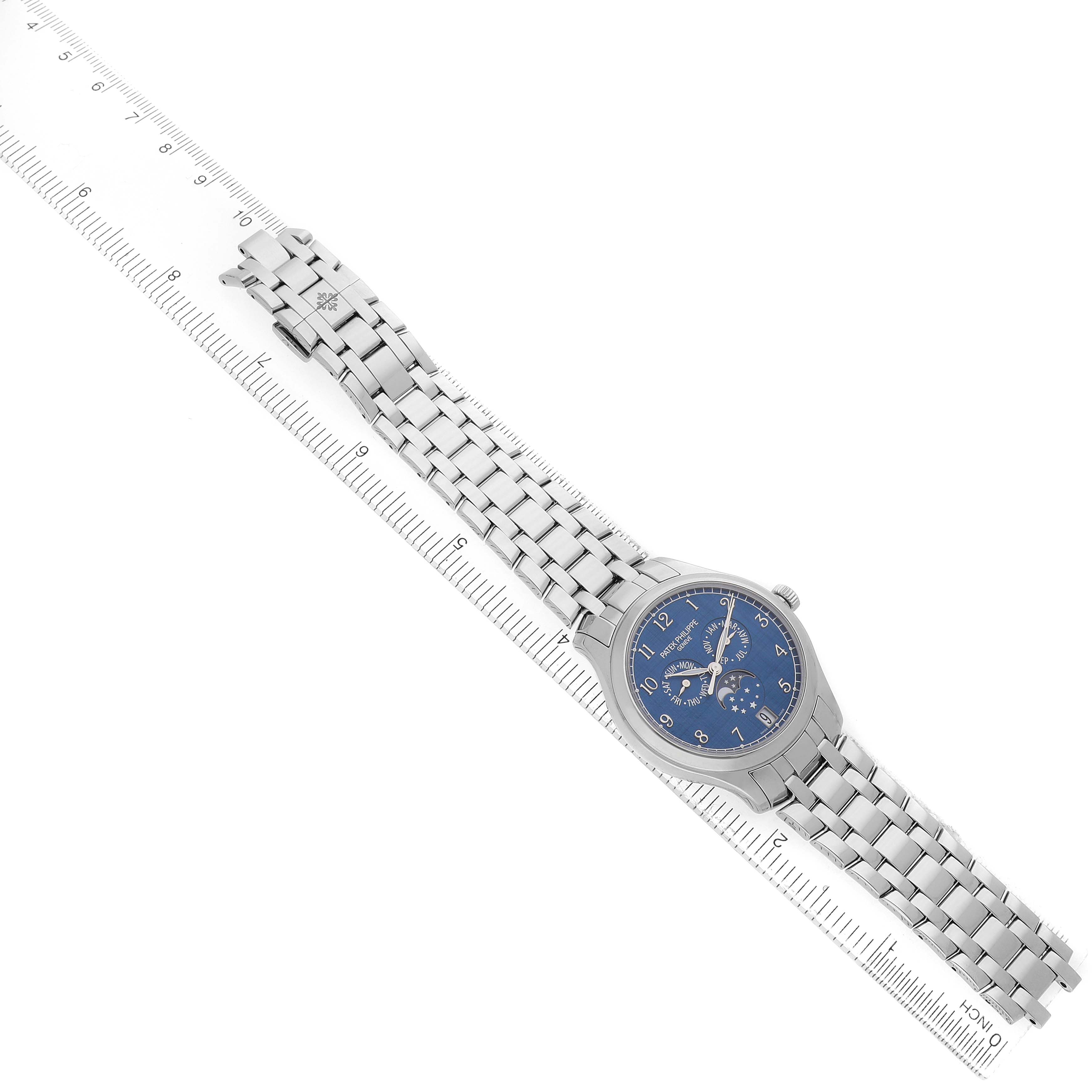 The image shows a Patek Philippe Complications 4947/1A-001 Men's Stainless Steel Blue Dial watch at an angled top view, displaying its face, bracelet, and part of a ruler.