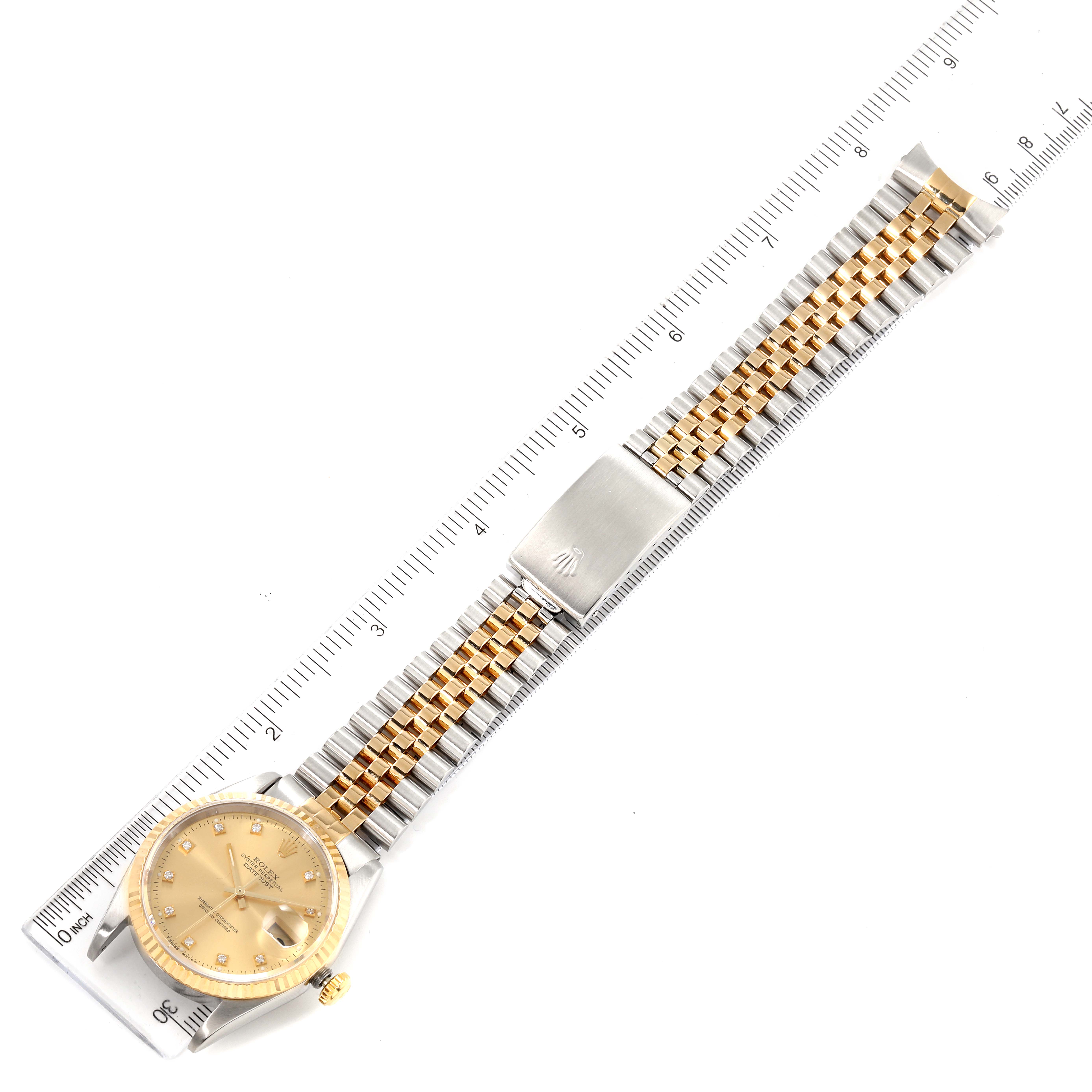 The image shows a top-down view of a Rolex Datejust 16233 Men
s Steel and Gold (two tone) Champagne Dial 16233 Men
s Steel and Gold (two tone) Champagne Dial watch, displaying its gold and silver bracelet and the face measured against a ruler.