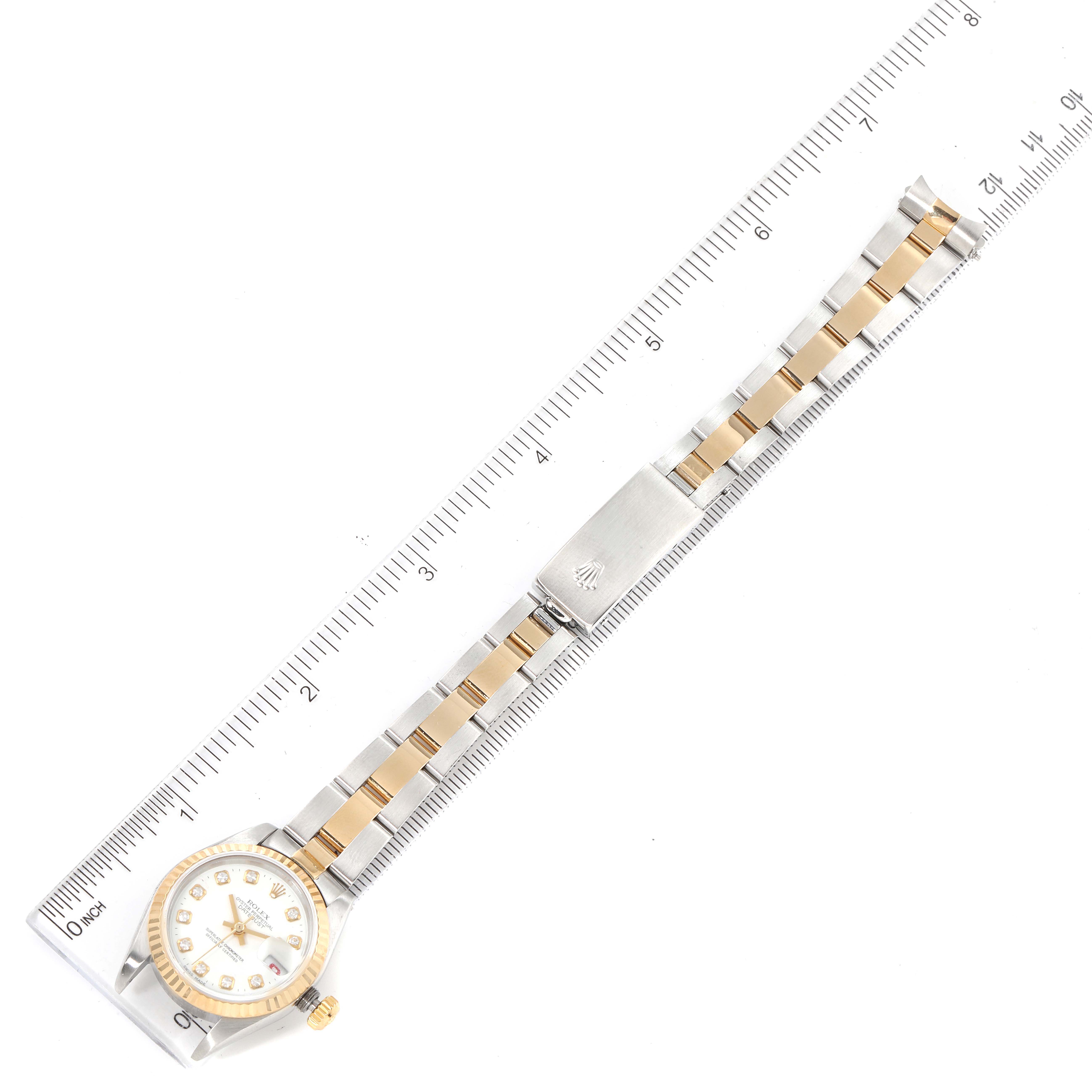 The image shows a Rolex Datejust 79173 Women's Steel and Gold (two tone) White Dial 79173 Women's Steel and Gold (two tone) White Dial watch laid flat with its bracelet and clasp extended, alongside a ruler for scale.