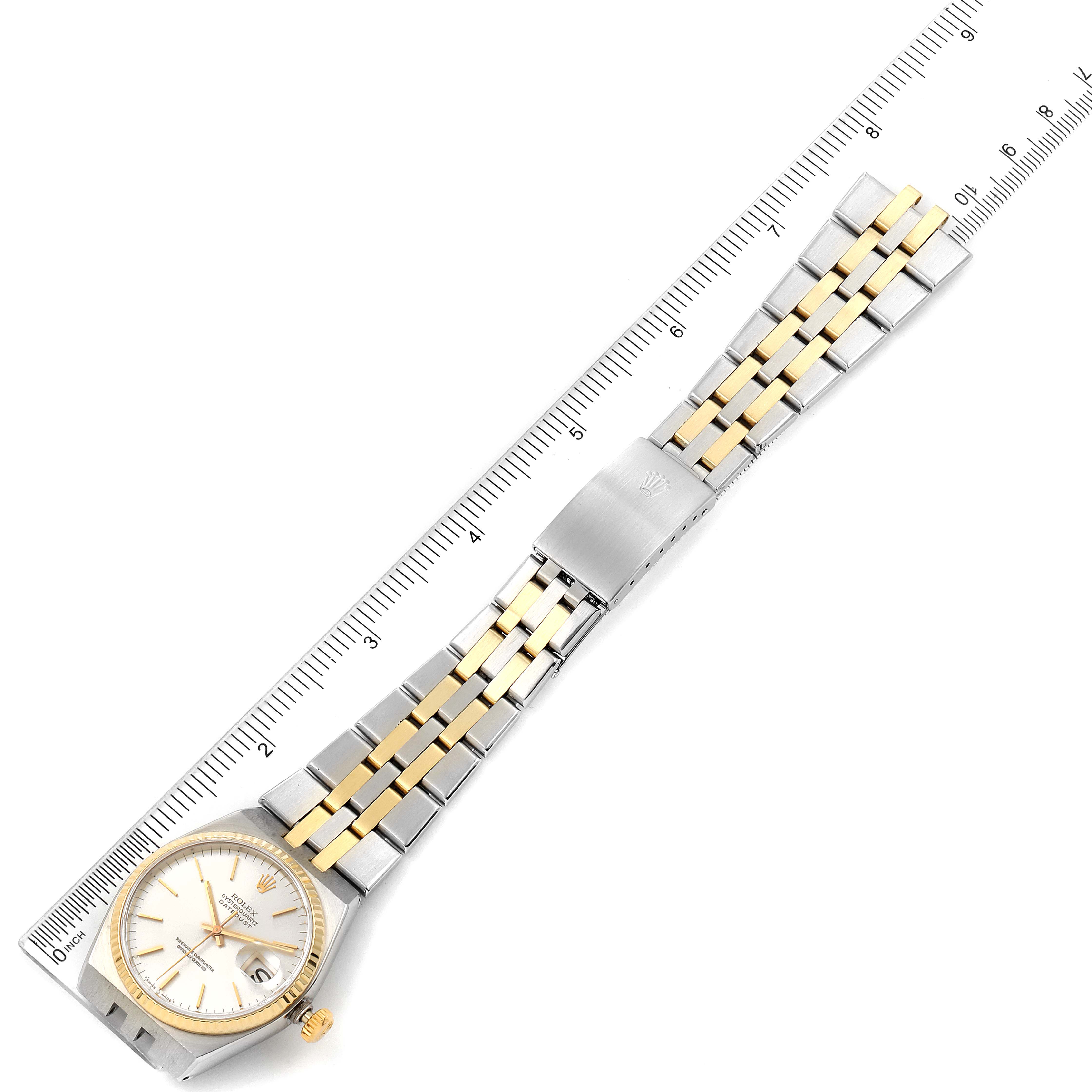 The Rolex Oysterquartz 17013 Men's Steel and Gold (two tone) Silver Dial 17013 Men's Steel and Gold (two tone) Silver Dial watch is shown from the top, displaying the full bracelet and watch face, alongside a measuring ruler.