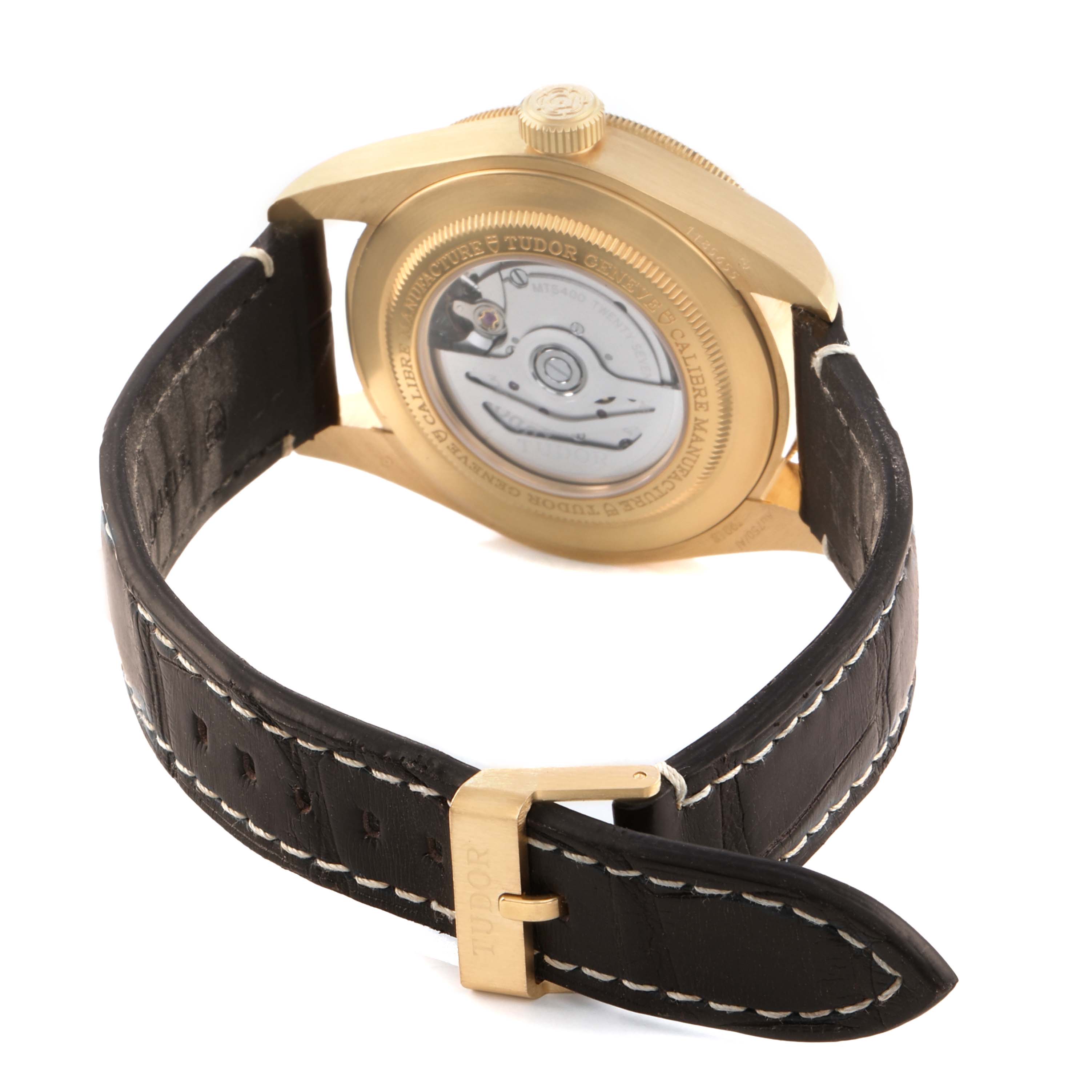 The Tudor Heritage Black Bay M79018V-0001 Men's Yellow Gold Green Dial watch is shown from the back, highlighting the movement and leather strap with buckle.