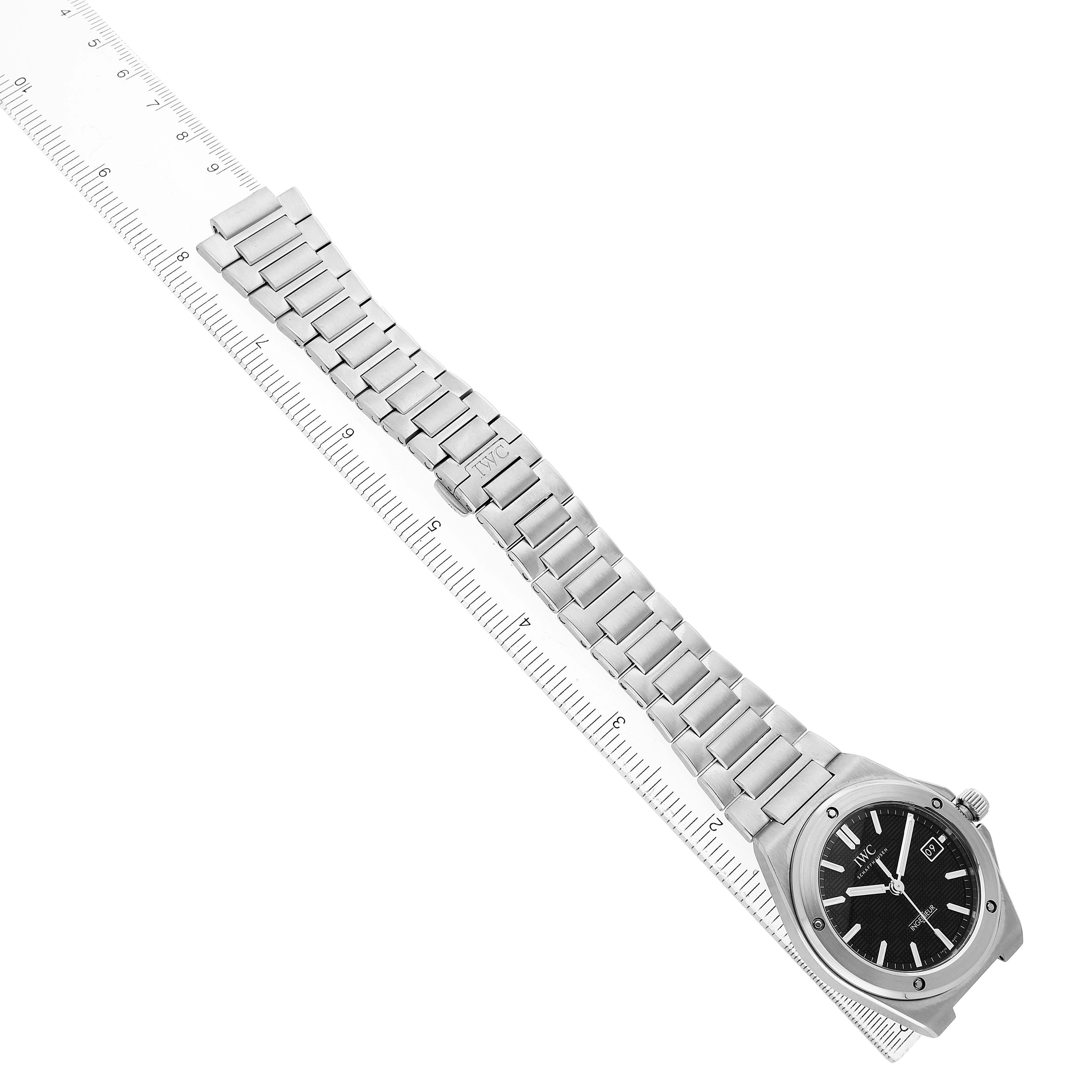 The IWC Ingenieur IW328901 Men's Stainless Steel Black Dial watch is shown from a top-down angle, displaying the dial, bezel, and bracelet alongside a ruler.