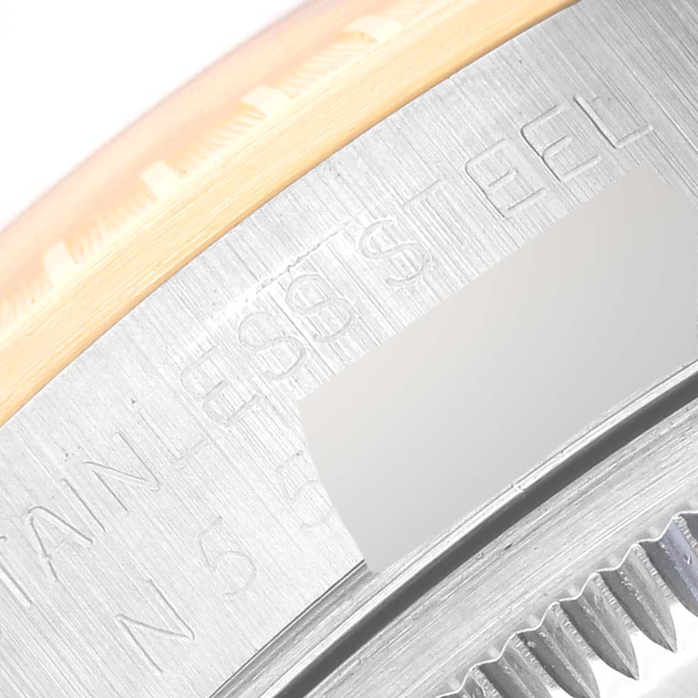 This close-up image of the Rolex Date 15223 Men's Steel and Gold (two tone) Champagne Dial 15223 Men's Steel and Gold (two tone) Champagne Dial model shows the edge of the bezel and part of the stainless steel case with engravings.