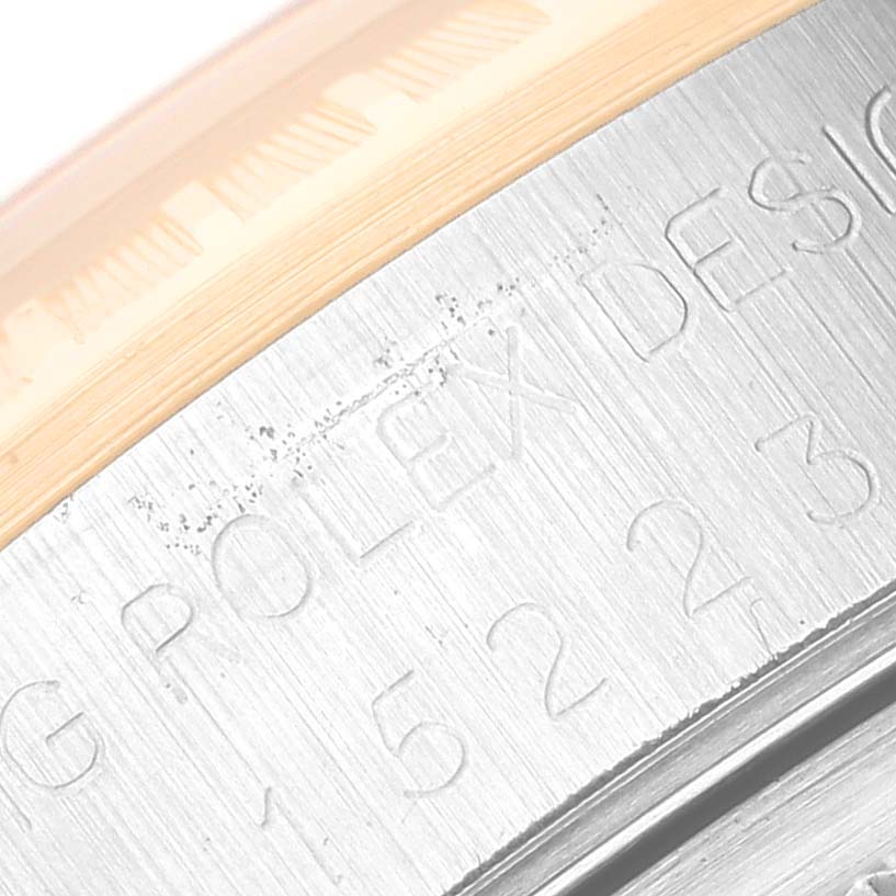 The image shows a close-up of the side of a Rolex Date 15223 Men's Steel and Gold (two tone) Champagne Dial 15223 Men's Steel and Gold (two tone) Champagne Dial model watch, featuring part of the engraved text and the edge of the bezel.