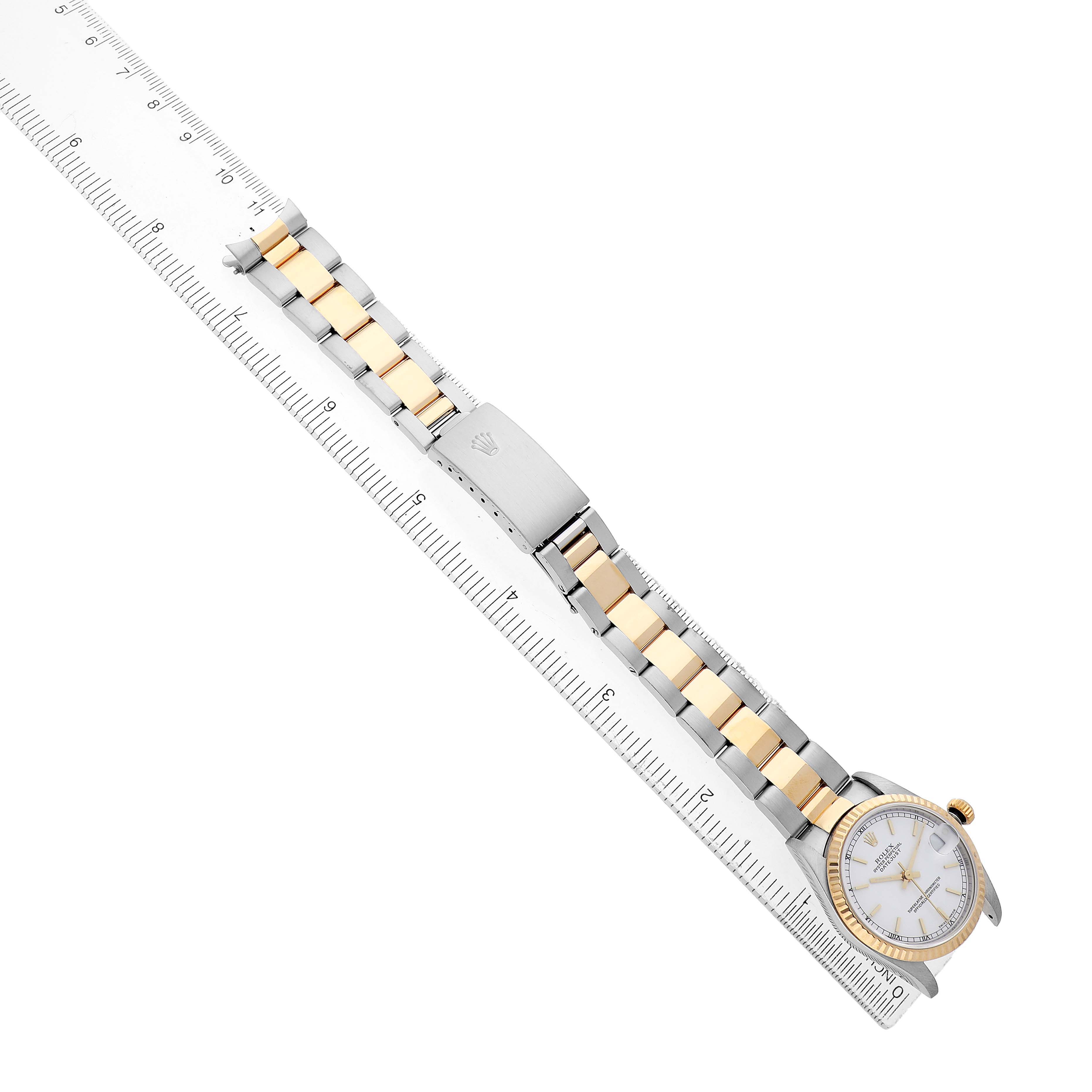 The Rolex Datejust 78273 Women's Steel and Gold (two tone) White Dial watch is shown at an angle with the full bracelet and clasp visible alongside a ruler for scale.