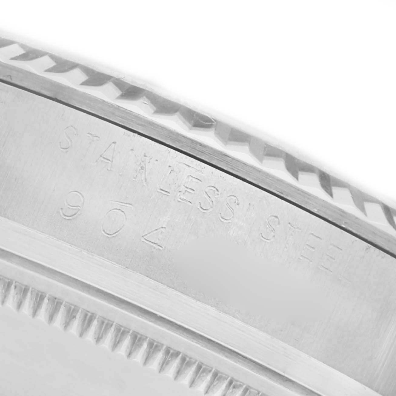The image shows a close-up of the Rolex Datejust 16014 Men's Stainless Steel Silver Dial 16014 Men's Stainless Steel Silver Dial's fluted bezel and the engraved "STAINLESS STEEL 904" markings.