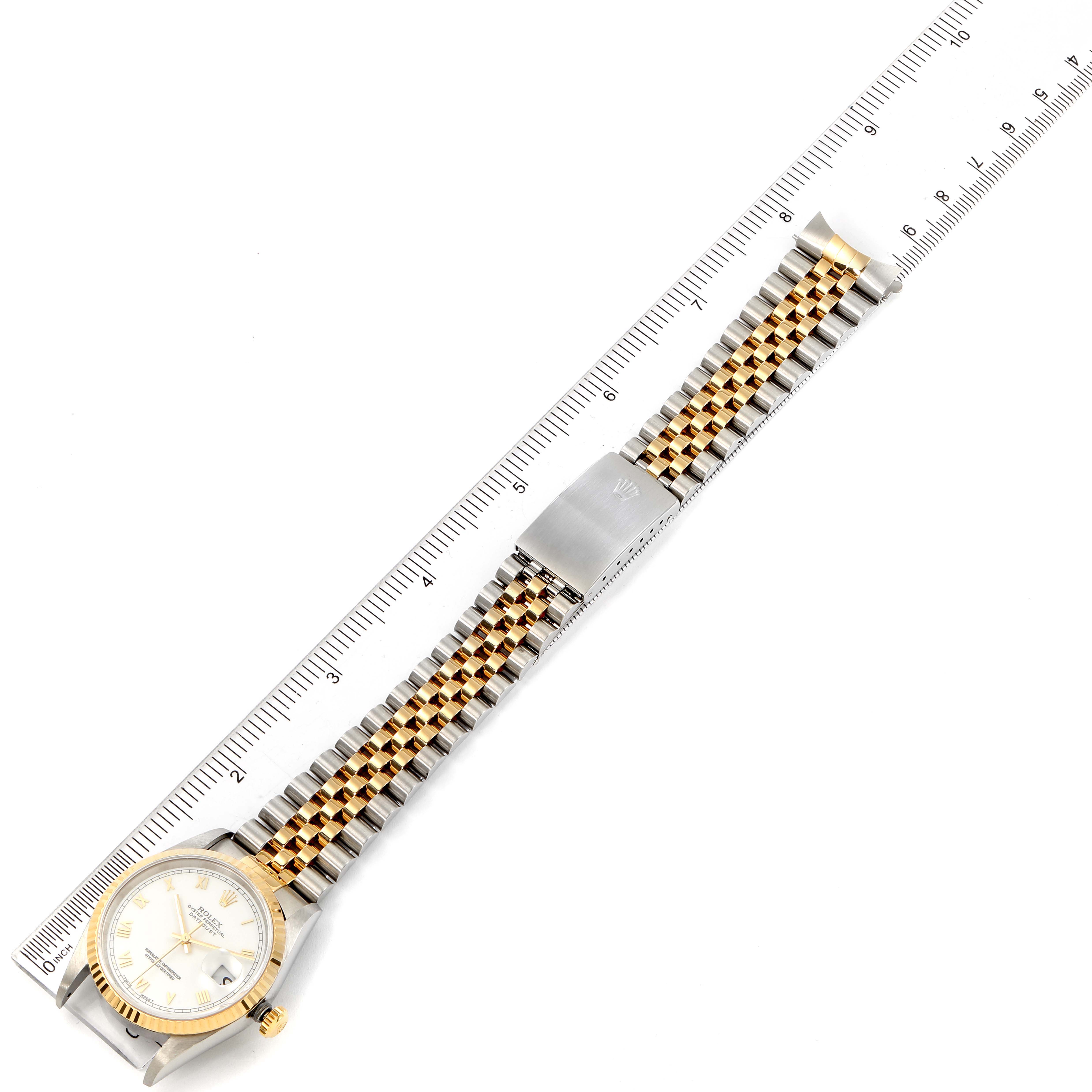 The image shows a Rolex Datejust 16233 Men's Steel and Gold (two tone) White Dial 16233 Men's Steel and Gold (two tone) White Dial watch laid flat, highlighting its face, jubilee bracelet, and the clasp, with a ruler for scale.