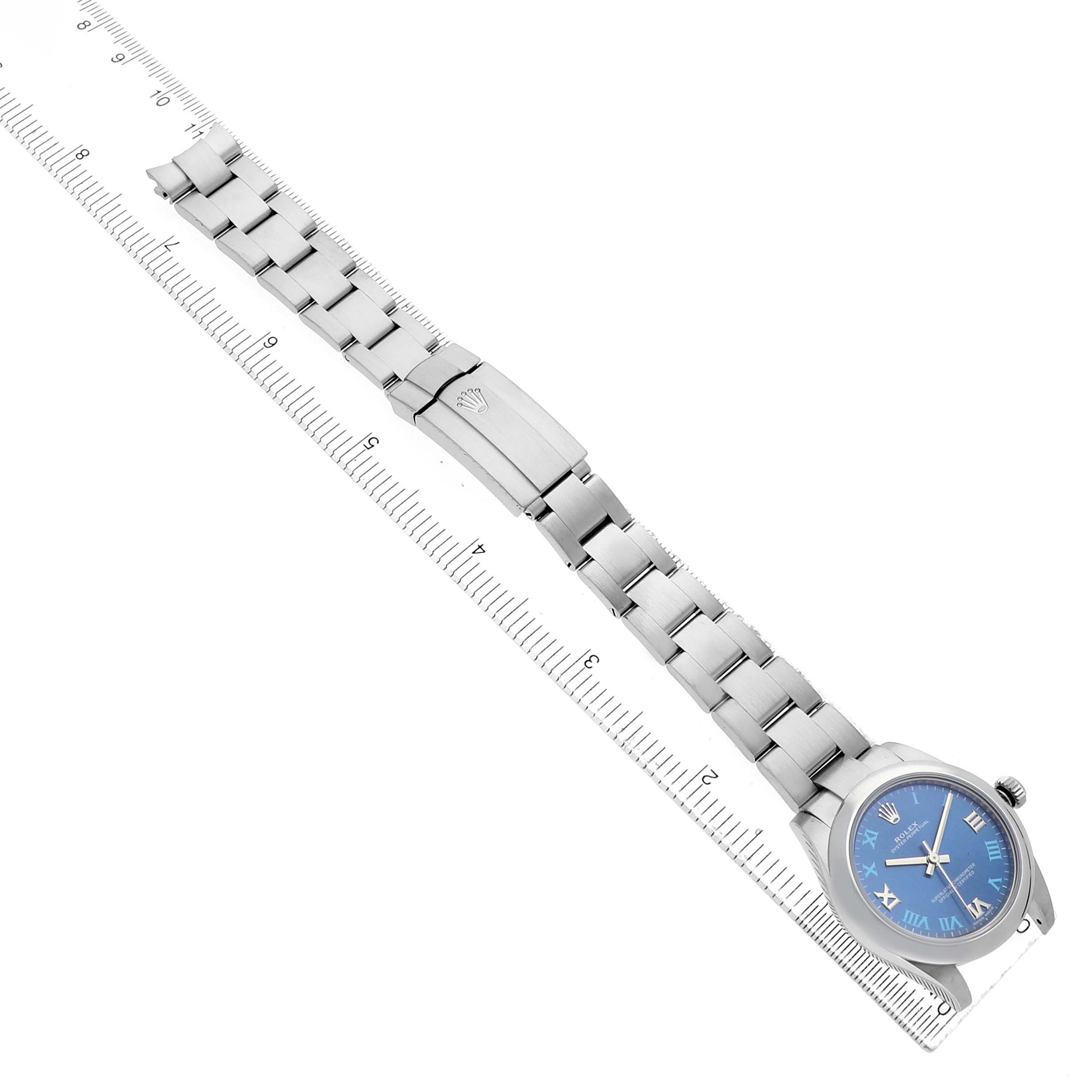 The Rolex Oyster Perpetual 177200 Women's Stainless Steel Blue Dial watch is shown at an angle displaying the bracelet, clasp, and blue dial with Roman numerals.