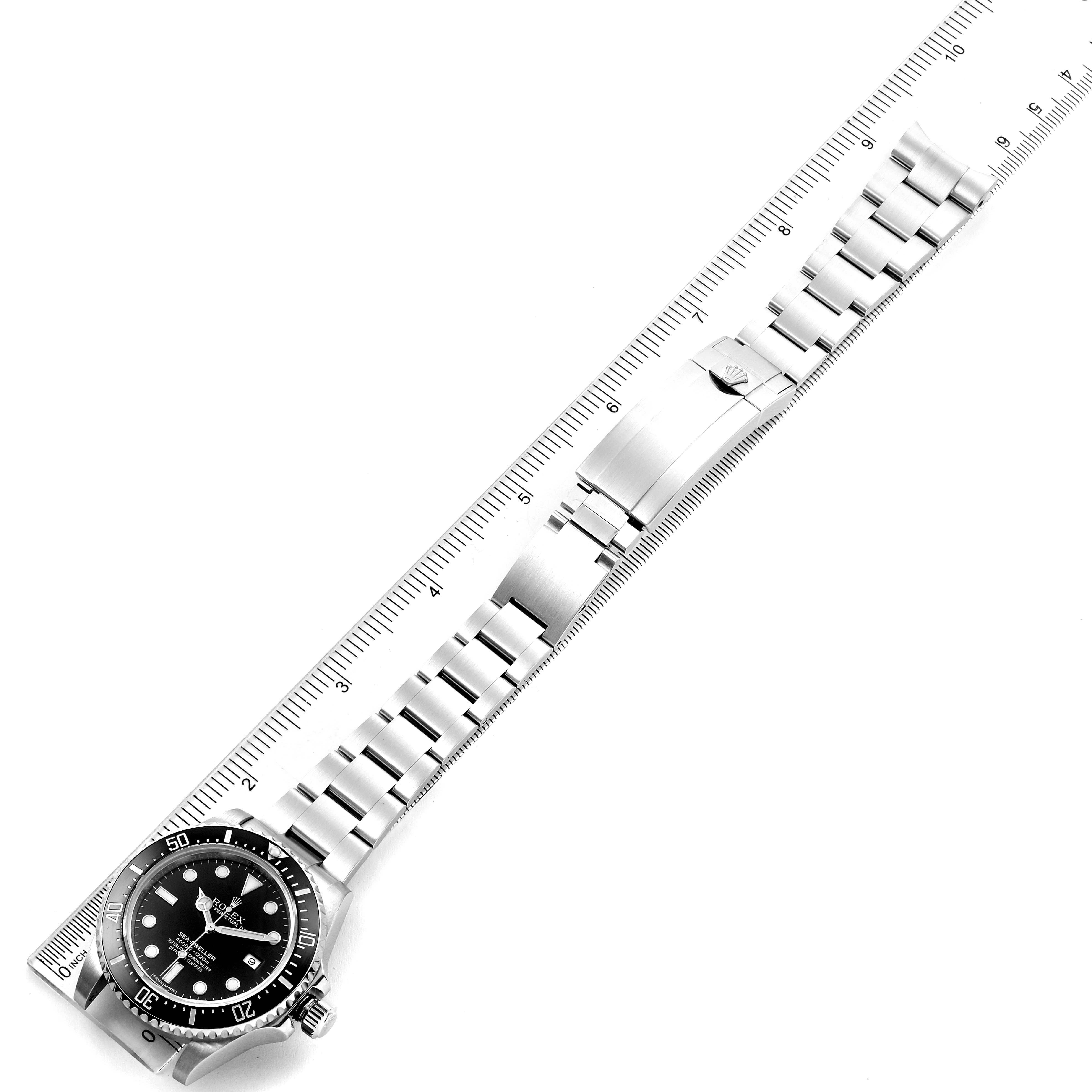 This image shows the Rolex Sea-Dweller 116600 Men
s Stainless Steel Black Dial 116600 Men
s Stainless Steel Black Dial watch lying flat with the face and entire bracelet extended next to a ruler.