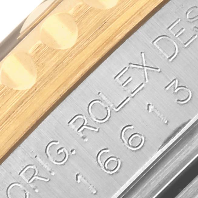 The image shows a close-up angle of a Rolex Submariner 16613 Men's Steel and Gold (two tone) Blue Dial 16613 Men's Steel and Gold (two tone) Blue Dial's bezel and case with engraved text.