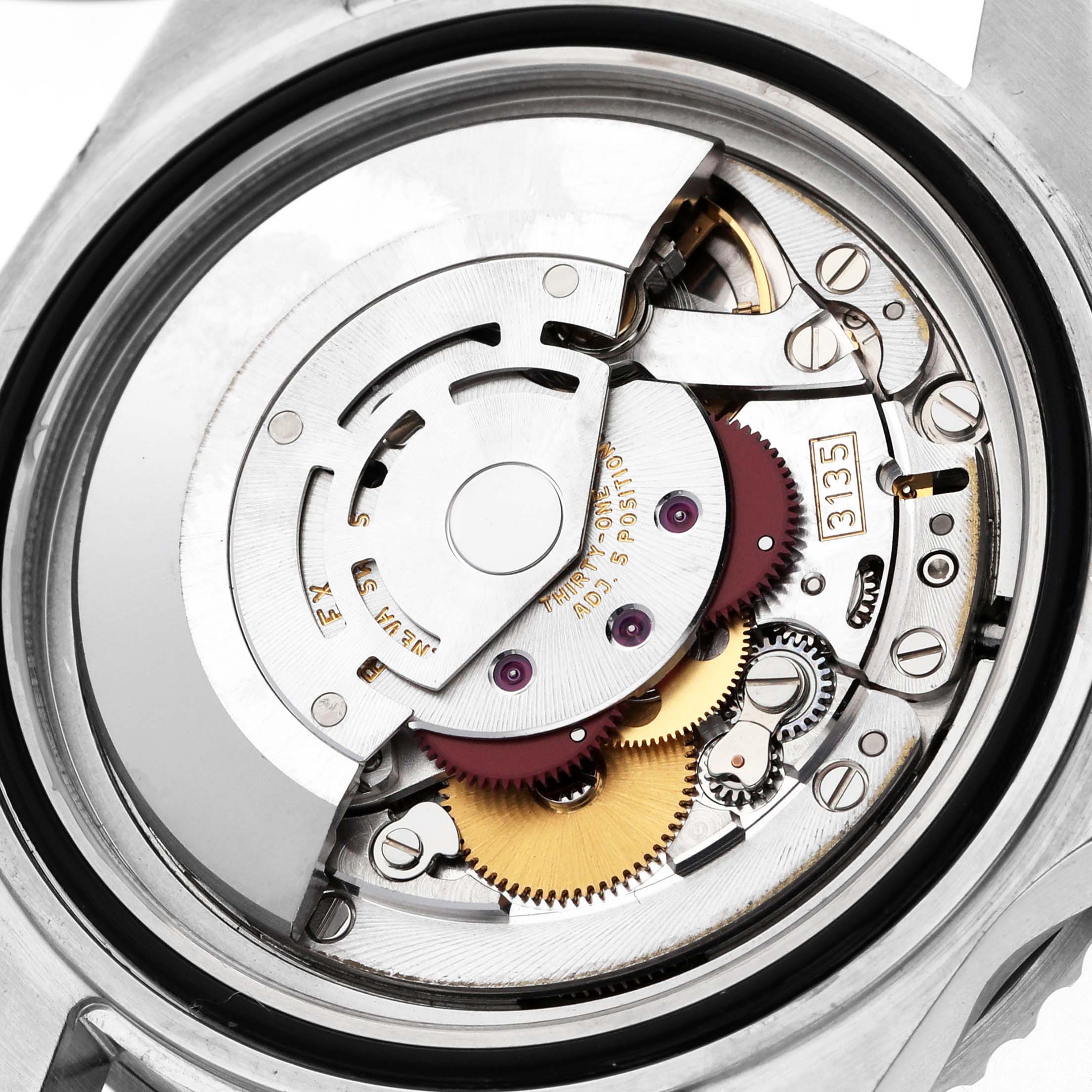 The image shows a close-up of the Rolex Submariner 16610 Men's Stainless Steel Black Dial's movement, highlighting gears and intricate mechanisms.