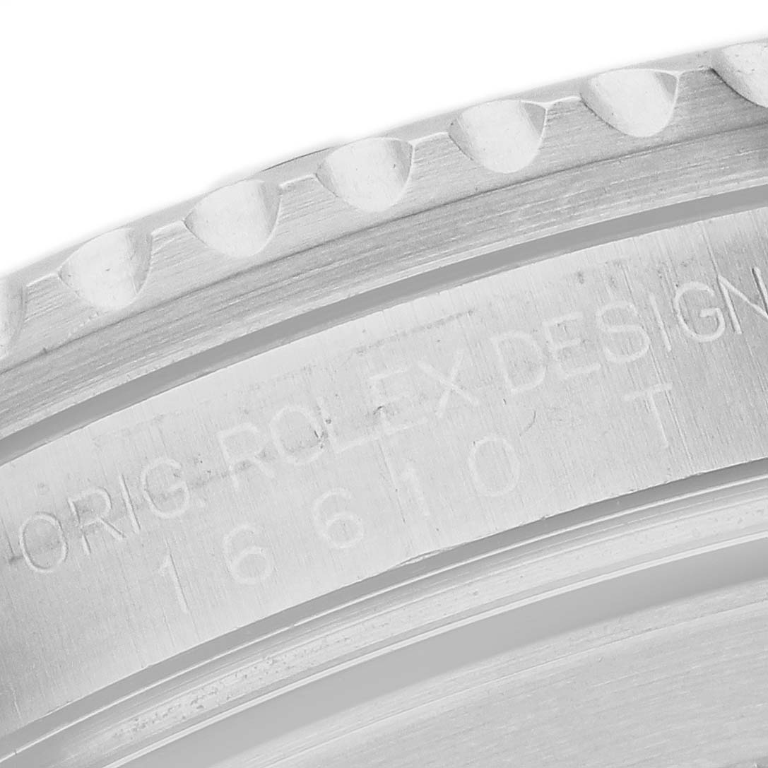 The image shows a close-up of the engraved bezel edge on a Rolex Submariner 16610 Men's Stainless Steel Black Dial watch.