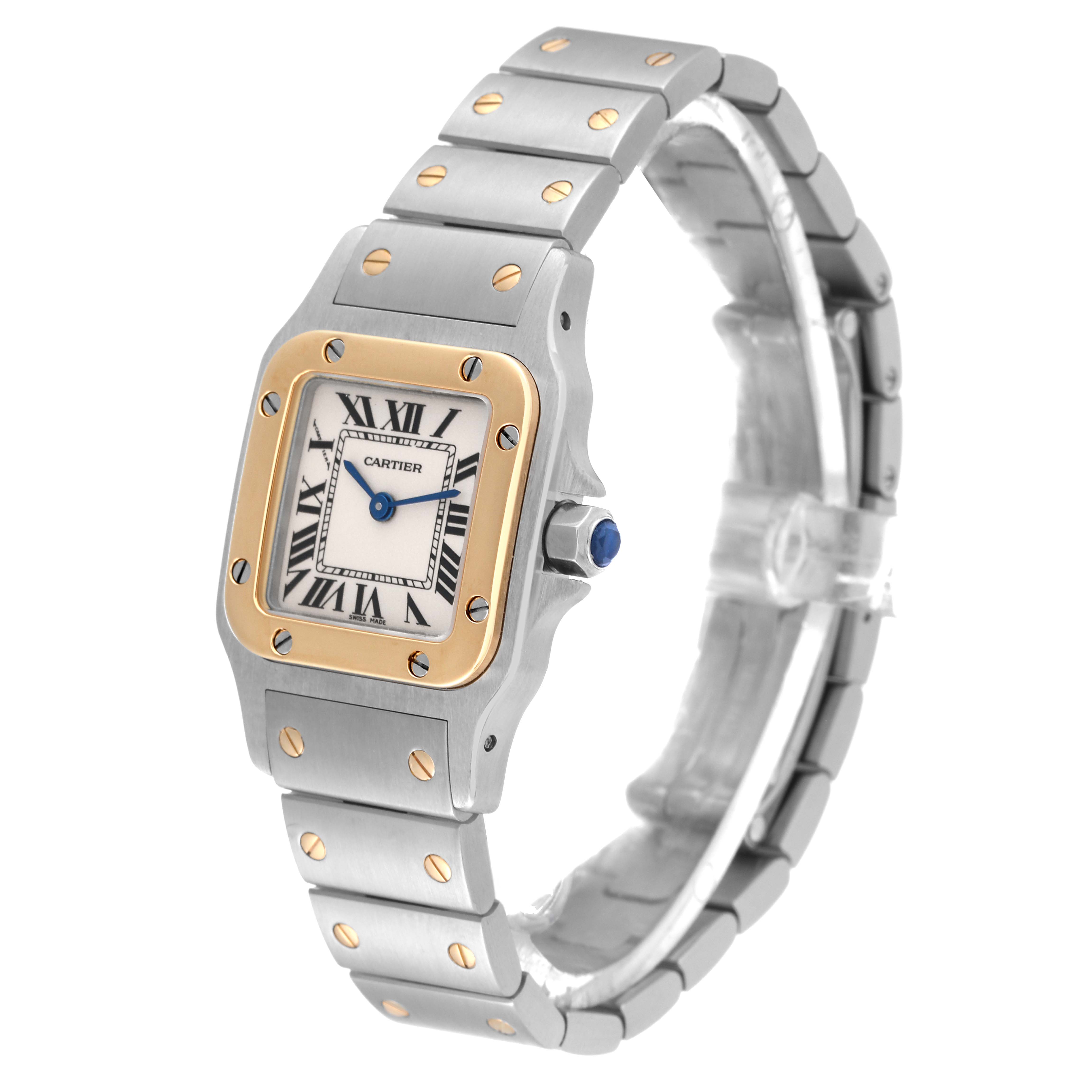 The Cartier Santos W20012C4 Women's Steel and Gold (two tone) Silver Dial W20012C4 Women's Steel and Gold (two tone) Silver Dial watch is shown at a slight angle, highlighting its face, band, and crown with a blue cabochon.