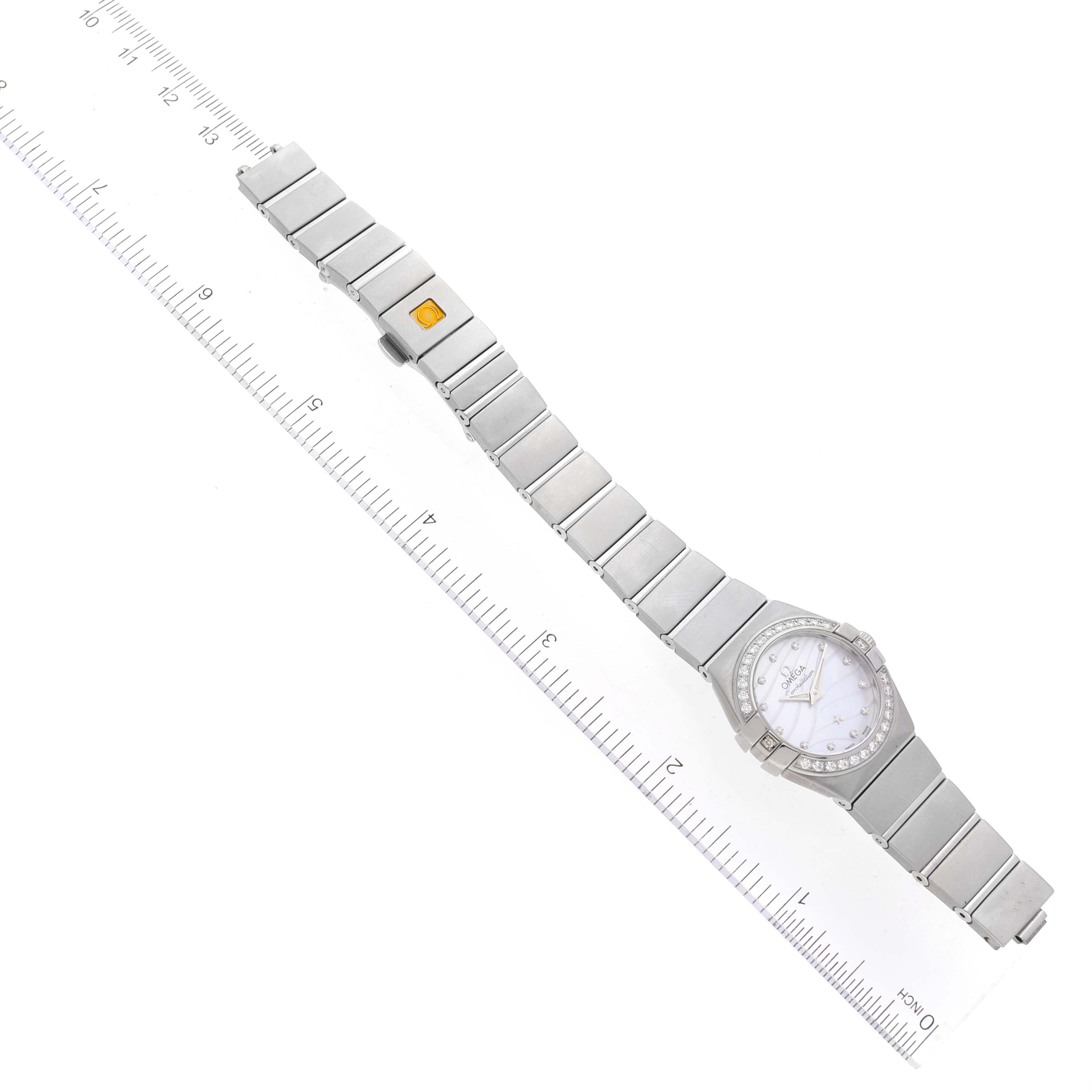The image shows the Omega 123.15.24.60.55.006 Women's Stainless Steel Mother of Pearl Dial 123.15.24.60.55.006 Women's Stainless Steel Mother of Pearl Dial Constellation Mother of Pearl Diamond Ladies Watch 123.15.24.60.55.006 laid flat next to a ruler.