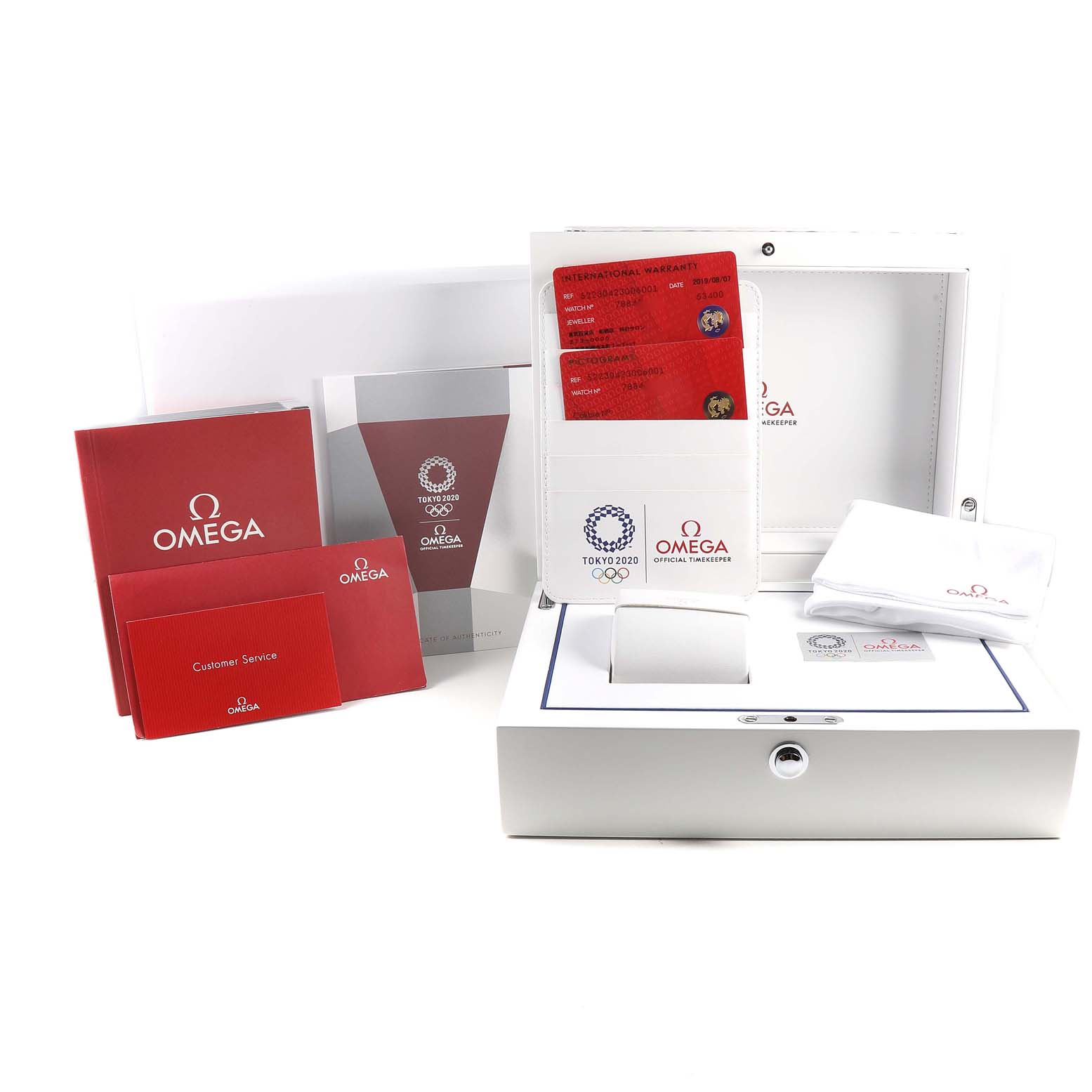 The image shows the warranty cards, manuals, and packaging of the Omega Speedmaster 522.30.42.30.06.001 Men's Stainless Steel Silver Dial 522.30.42.30.06.001 Men's Stainless Steel Silver Dial, including a white box with Tokyo 2020 branding.