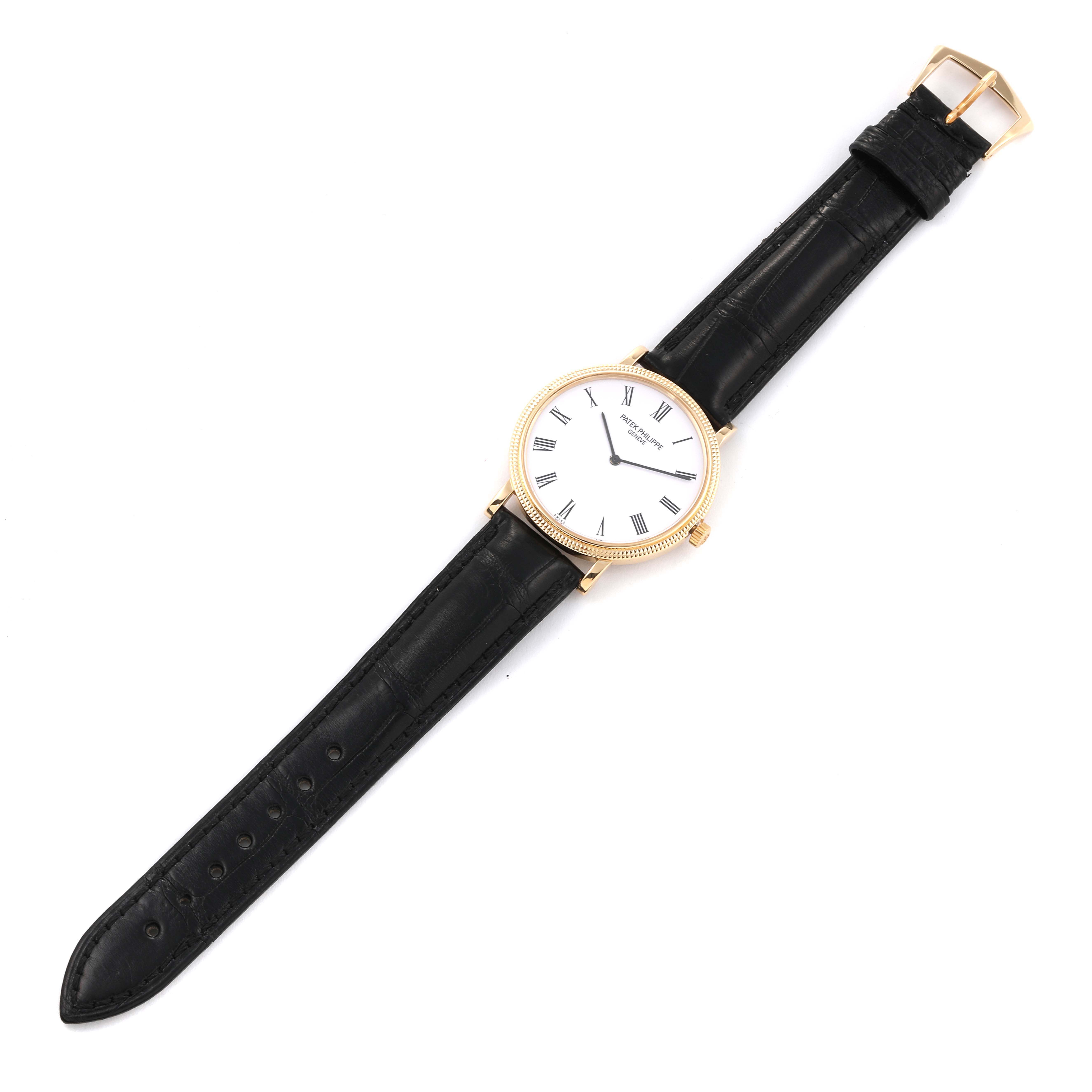 The image shows a Patek Philippe Calatrava 5120J Men's Yellow Gold White Dial 5120J Men's Yellow Gold White Dial watch, viewed from above, displaying its face, black leather strap, and gold buckle.