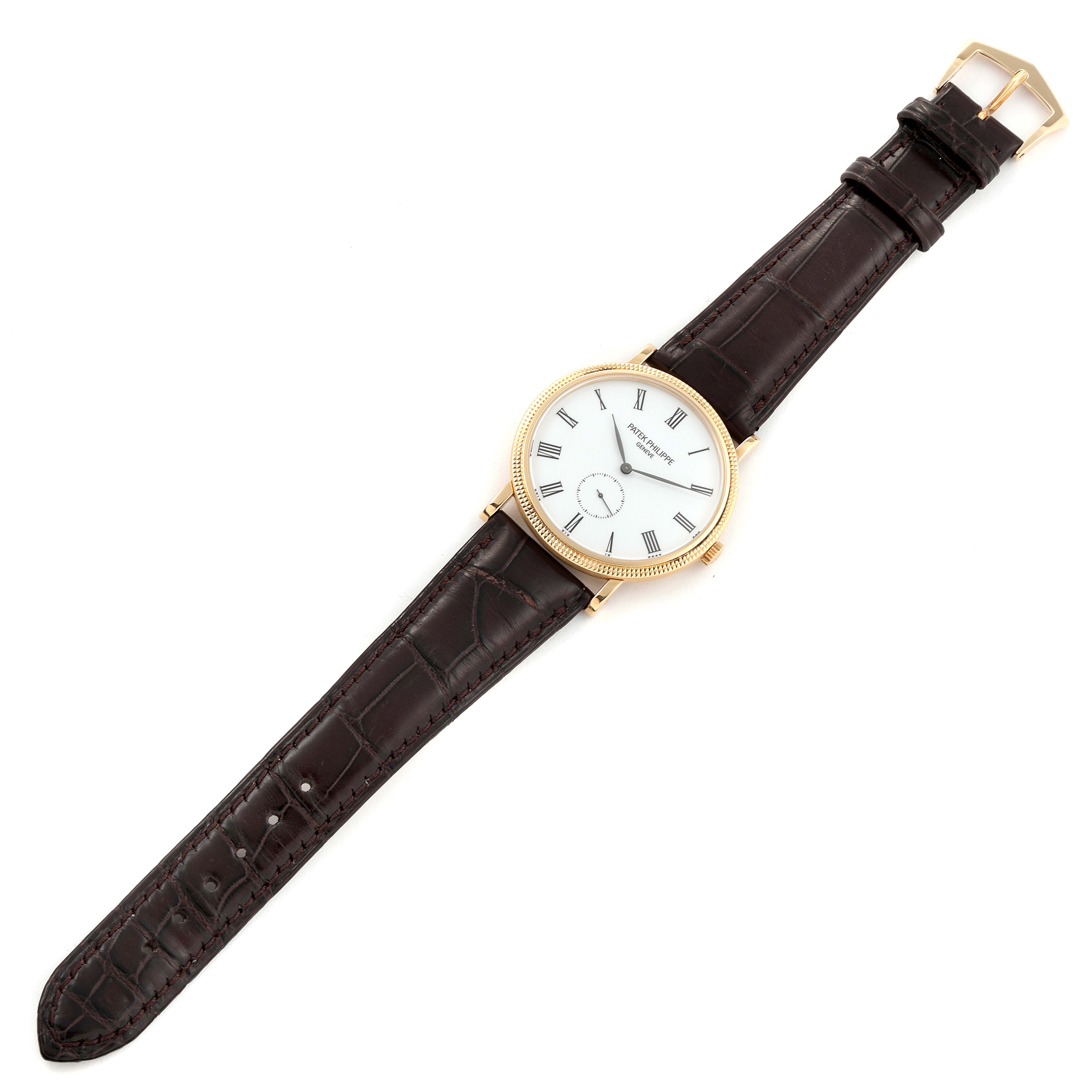 The image shows a top view of a Patek Philippe Calatrava 5119J Men
s Yellow Gold White Dial 5119J Men
s Yellow Gold White Dial watch, featuring its dial, case, and leather strap.