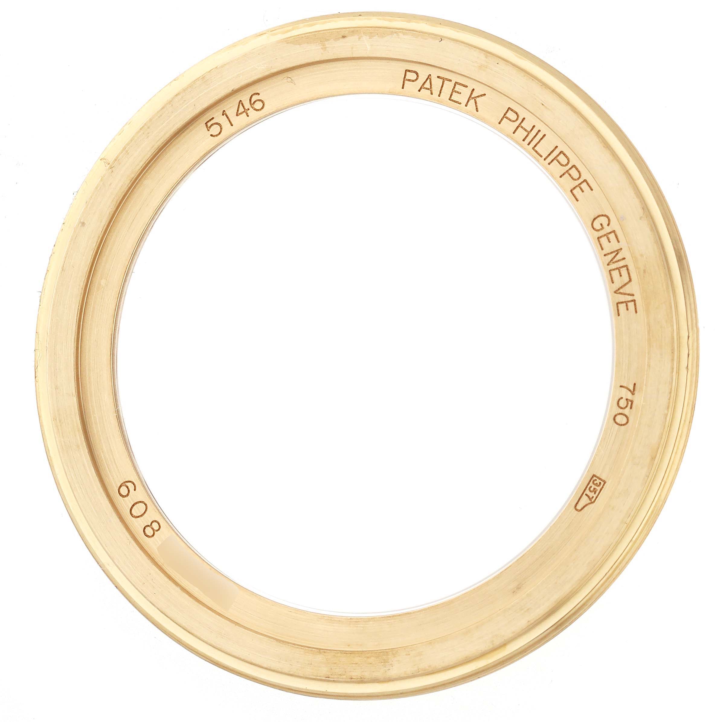 The image shows a gold bezel from a Patek Philippe Complications 5146J-001 Men's Yellow Gold White Dial 5146J-001 Men's Yellow Gold White Dial model, viewed from above with inscriptions on the inner side.