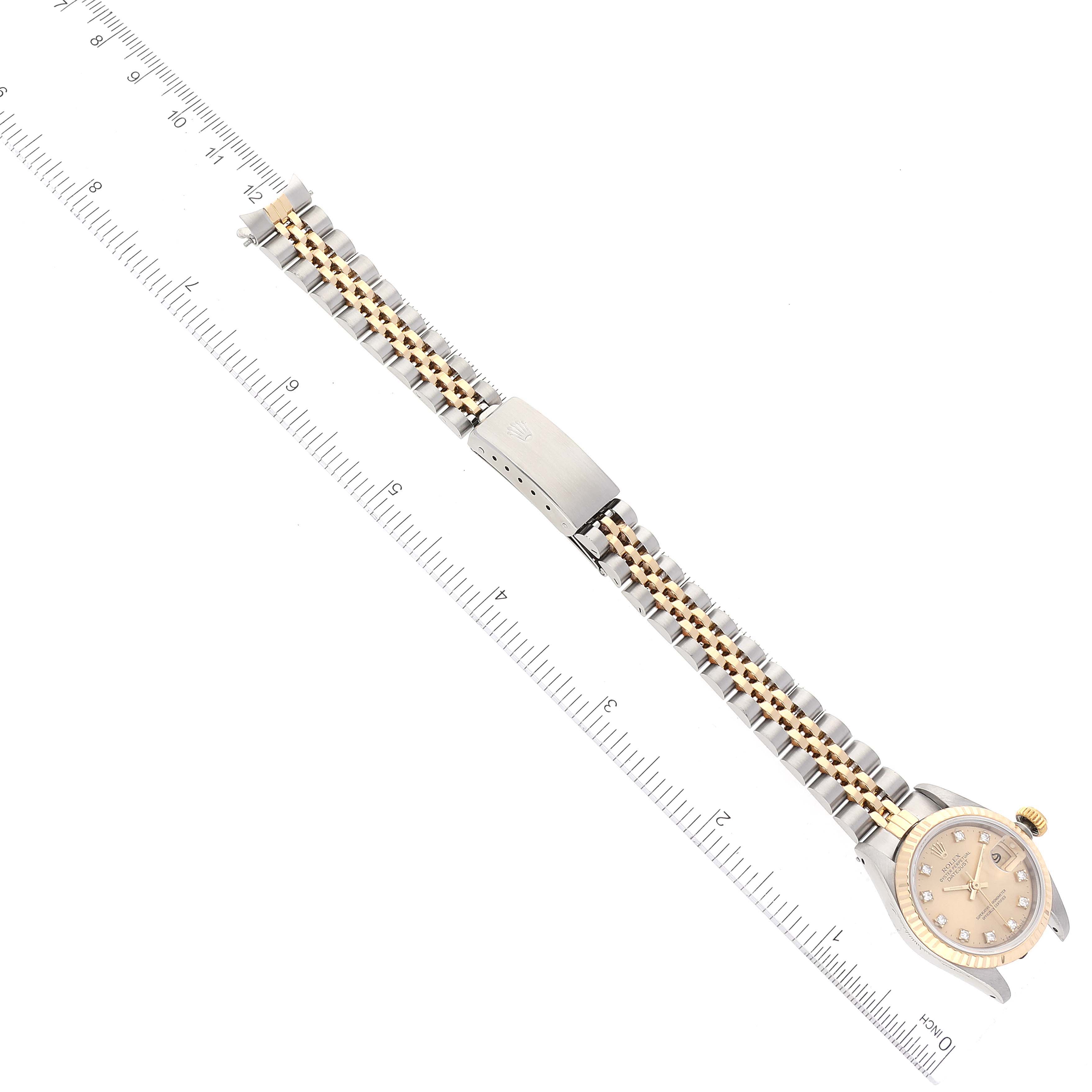 The image shows the Rolex Datejust 69173 Women's Steel and Gold (two tone) Champagne Dial 69173 Women's Steel and Gold (two tone) Champagne Dial watch from a top view, displaying its bracelet and clasp alongside a ruler for size reference.