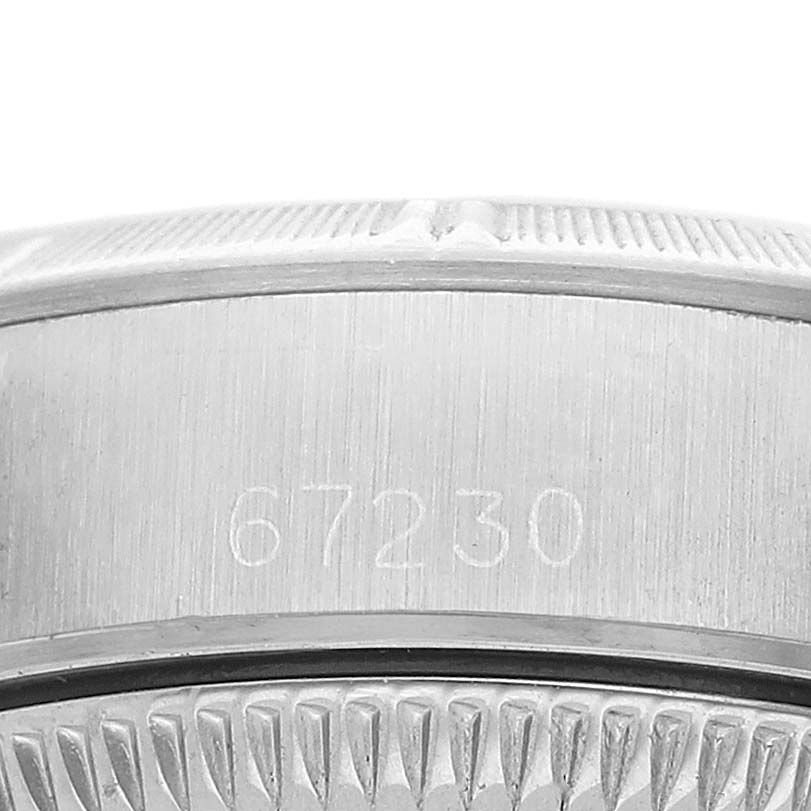 This image shows a close-up of the case side and bezel of a Rolex Oyster Perpetual 67230 Women's Stainless Steel Silver Dial watch, focusing on engraved details.