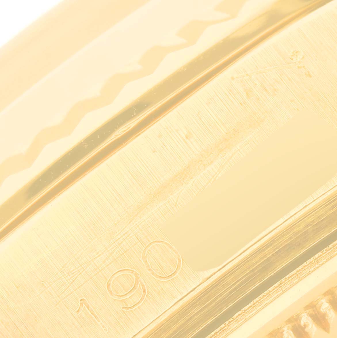 This close-up image of a Vintage Collection Rolex watch focuses on a portion of its gold-colored band with engraved numbers.